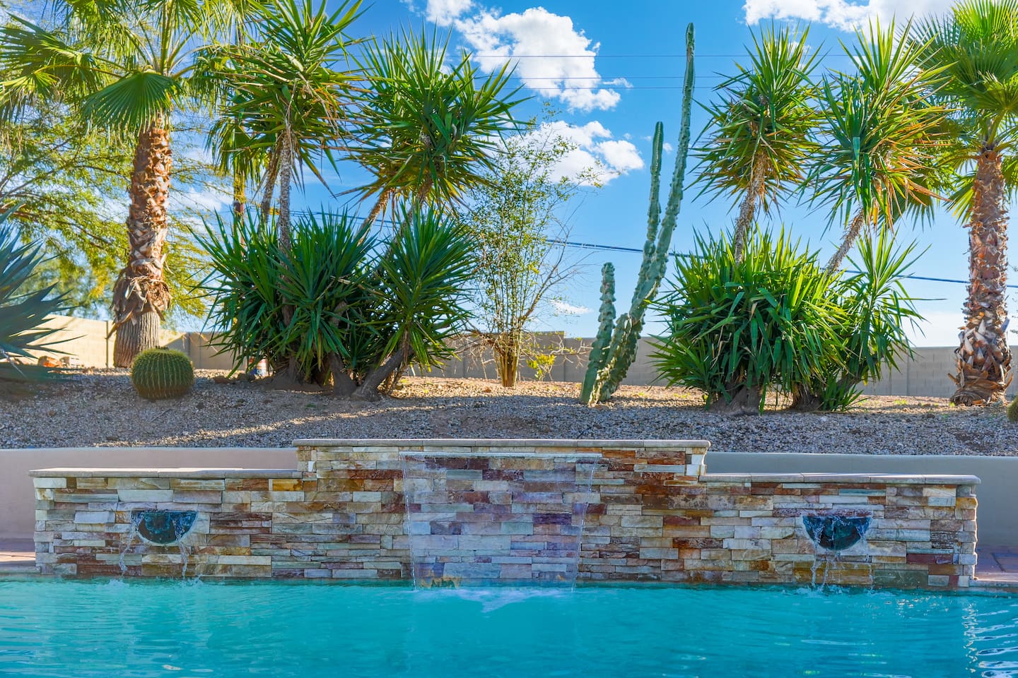 Close-up of the stone waterfall feature adding a calming, resort-like touch to the pool area.