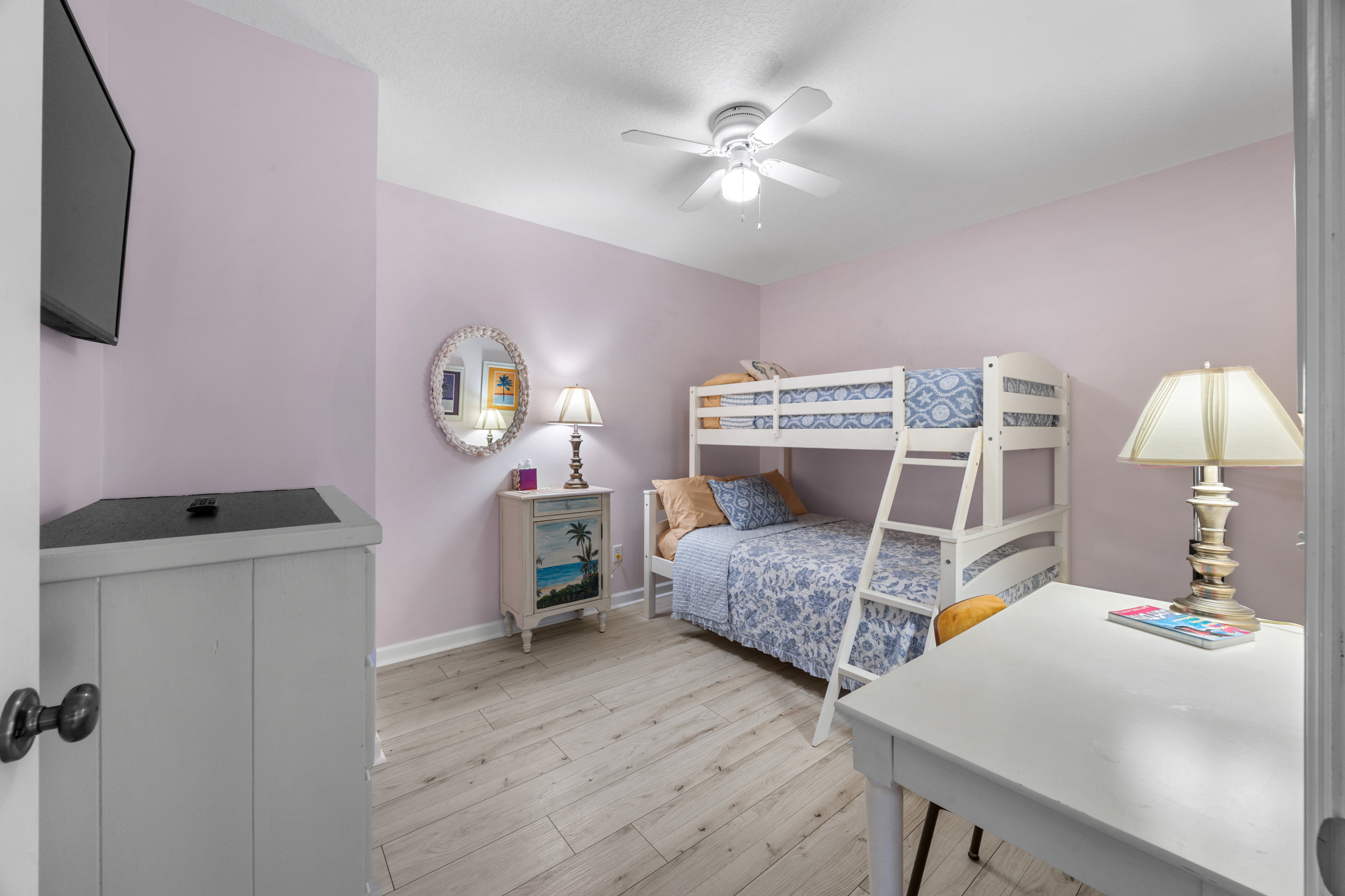 Charming bunk room with pastel tones, workspace, and coastal décor — perfect for kids or extra guests.