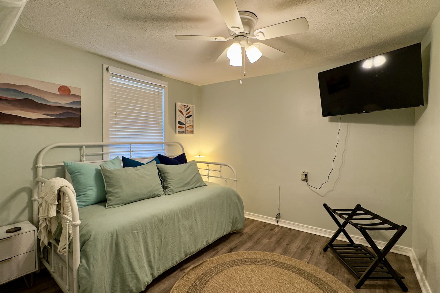 Charming bedroom with a comfy daybed, calming decor, and wall-mounted TV.
