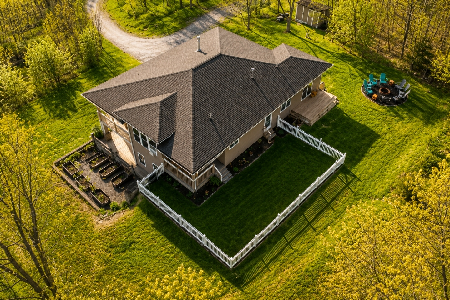 This aerial view showcases a stunning, modern home surrounded by lush greenery, featuring expansive outdoor living spaces and a serene setting, perfect for a luxurious retreat. 