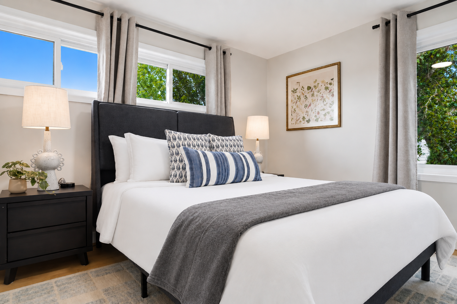 This serene bedroom features a comfortable bed, neutral decor, and large windows that fill the room with natural light, creating a calm and restful retreat.