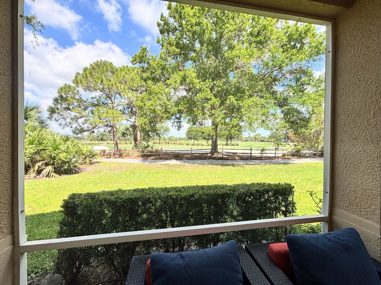 Peaceful outdoor view overlooking green space, mature trees, and a scenic walking path.