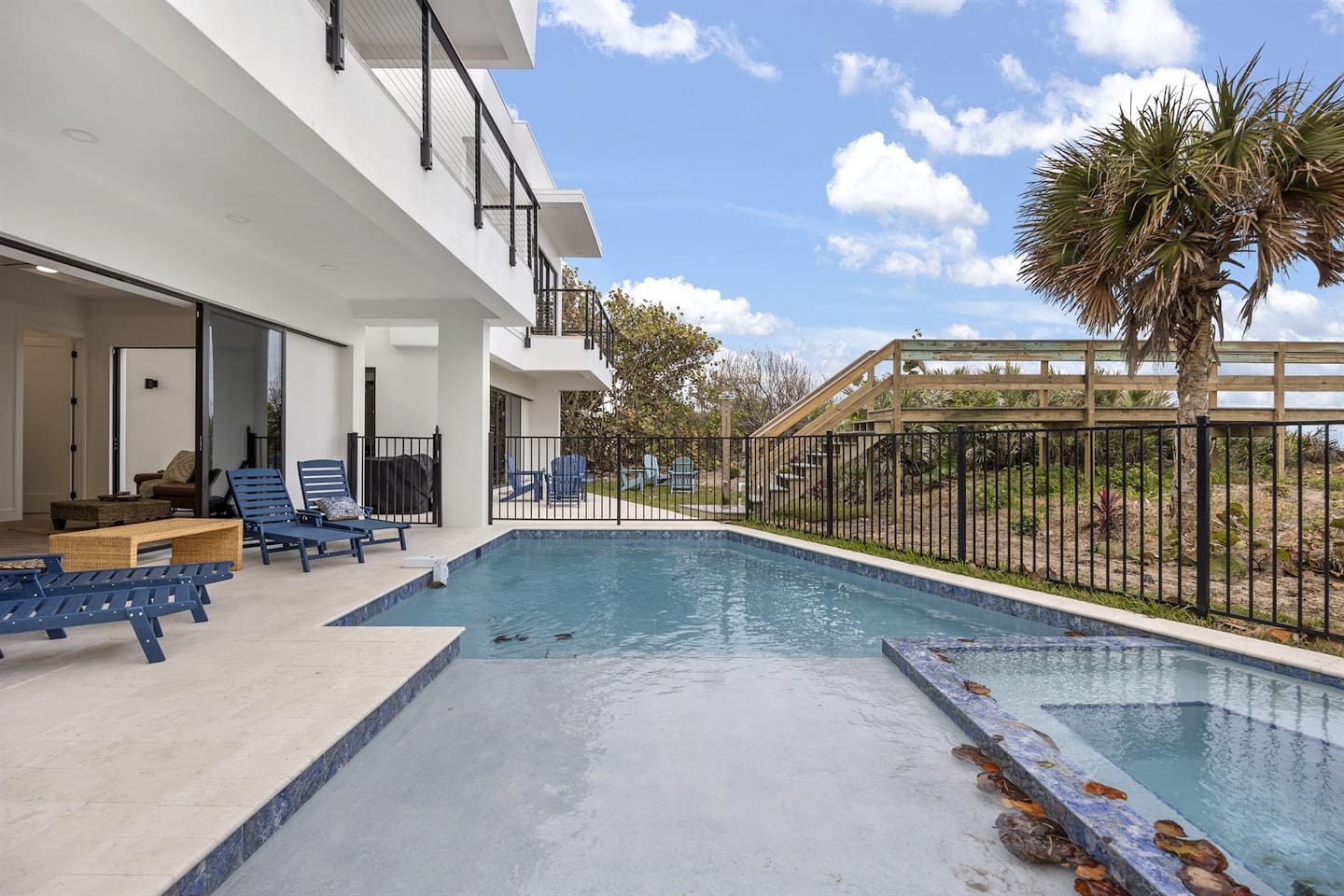 From a side angle, the exterior showcases a serene swimming pool, with comfortable relaxing chairs nearby, all surrounded by lush greenery, creating a perfect tranquil retreat for relaxation and enjoyment of nature