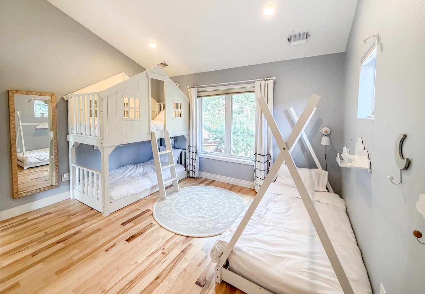 This bright bedroom combines fun and comfort, featuring a playful bunk bed, a cozy teepee-style bed, and a soft rug for reading, playing, or relaxing