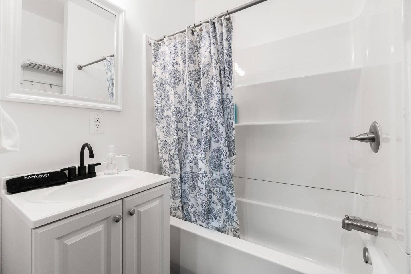 Bright and clean bathroom featuring a relaxing tub, mirror, fresh towels, and essentials like soap, shampoo, and conditioner for your convenience.