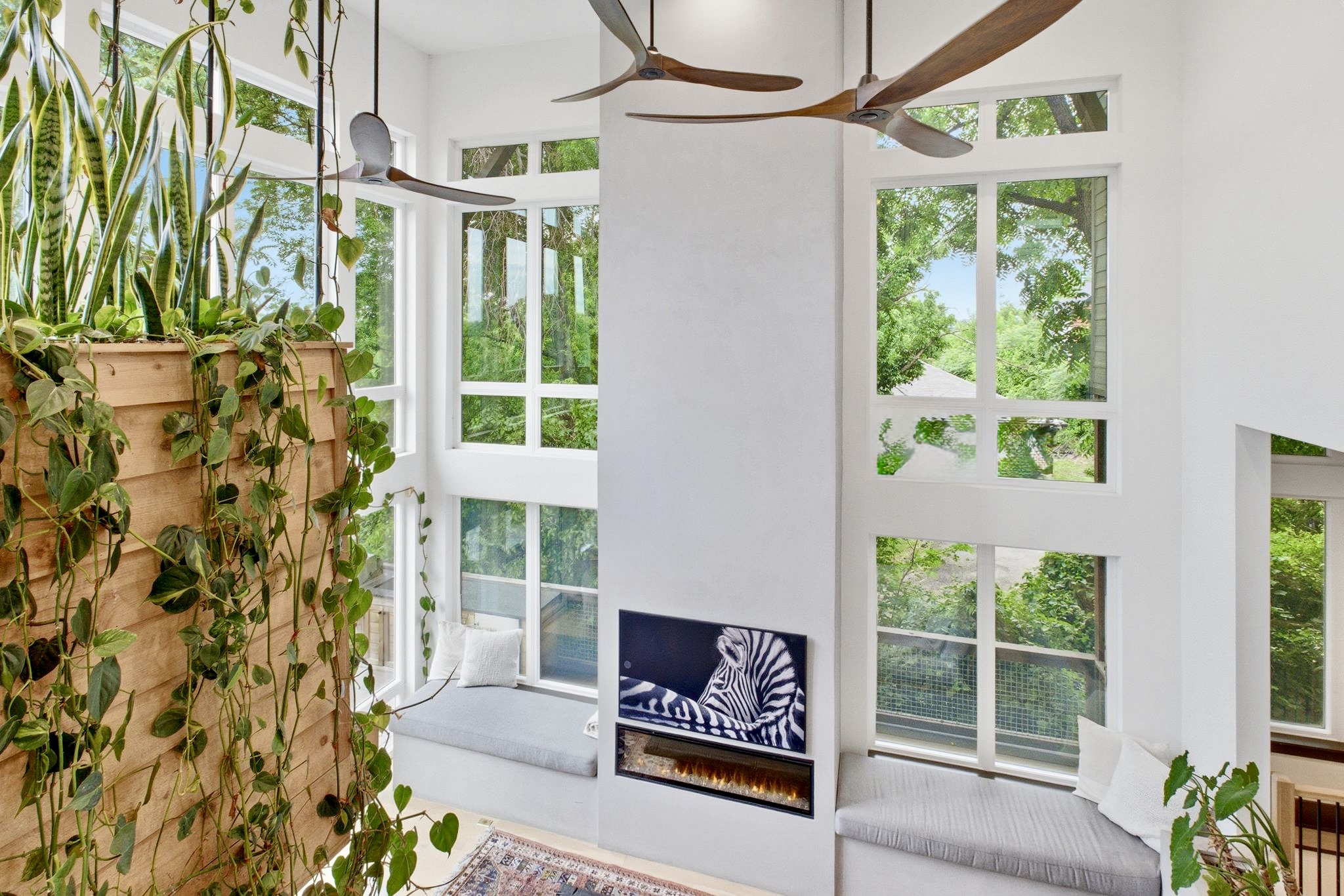 Tall arched windows frame the greenery outside, bathing this cozy reading nook in natural light.
