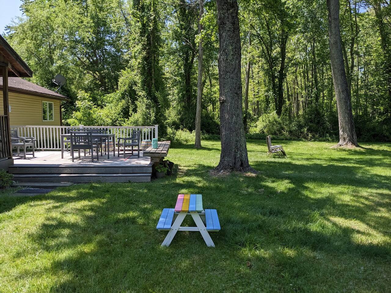 Side view of back yard. Children's picnic table in the foreground.