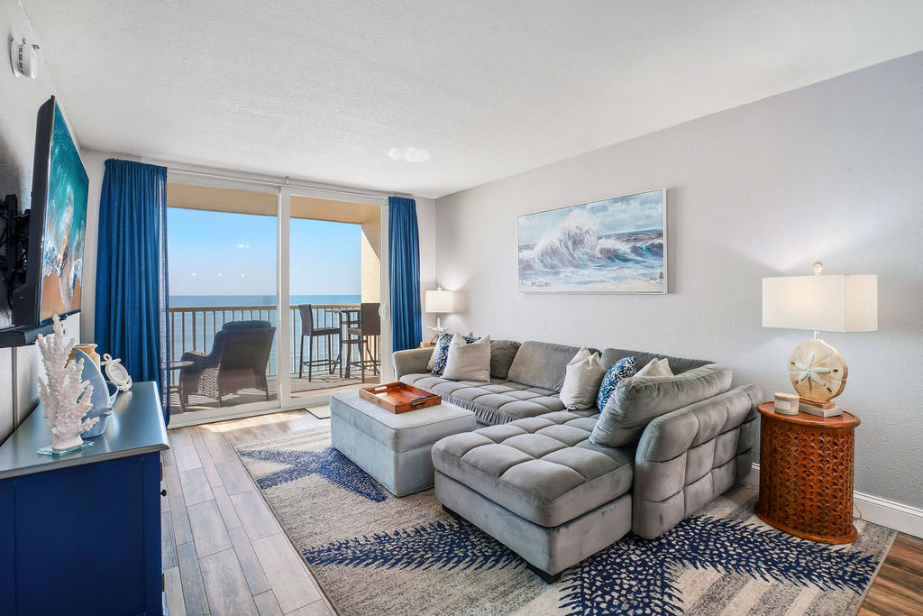 Beachfront living room with private balcony access, ocean views, and comfortable coastal furnishings for the perfect vacation rental getaway.
