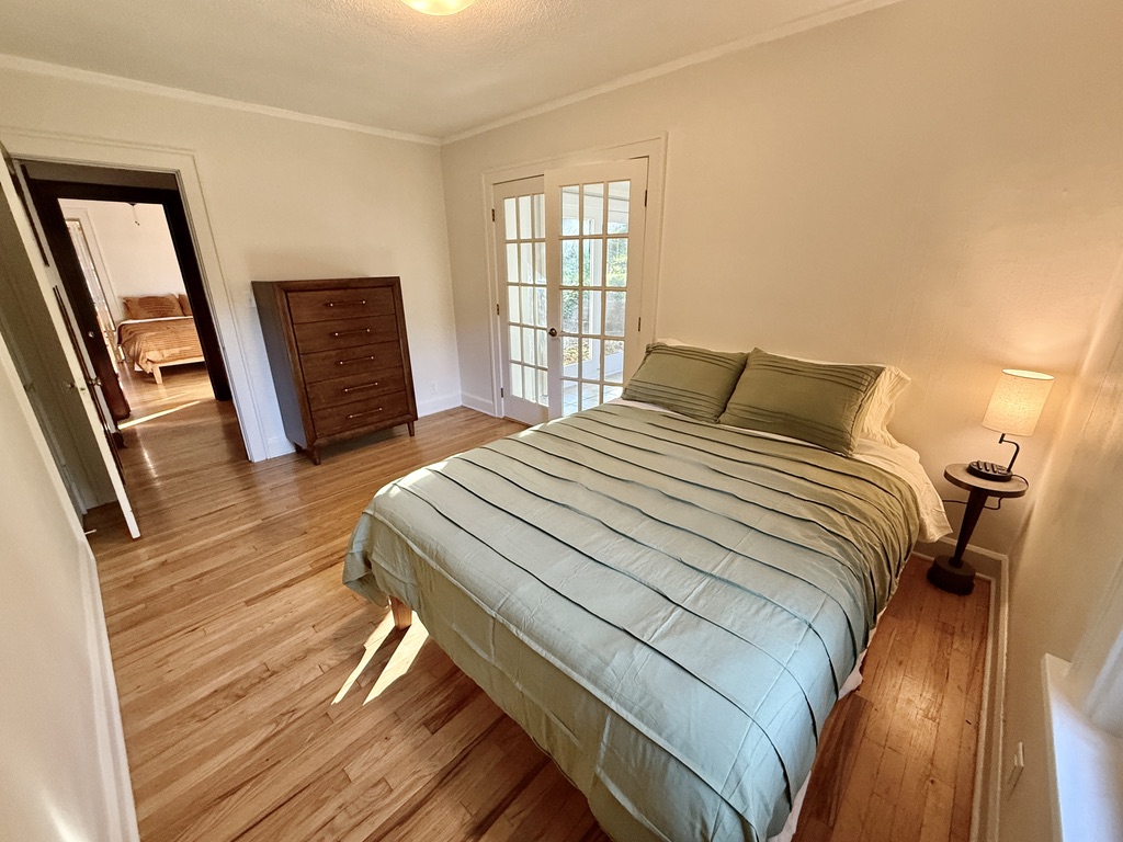 The office is connected to the first bedroom on the right, that features a plush queen bed, dresser, closet, and charging lamp.