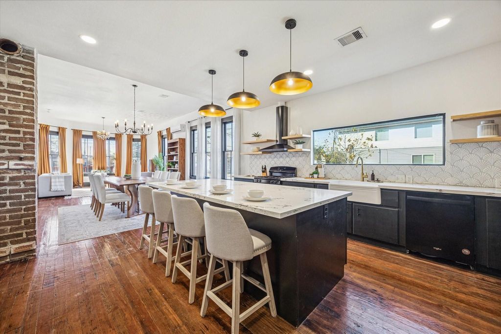 This open, airy home was made for modern living, with casual bar seating flowing into an open dining area, hardwood floors underfoot, rich millwork, tall windows, and stylish lighting all wrapped in the warmth of nearly 100 years of history, ready for your