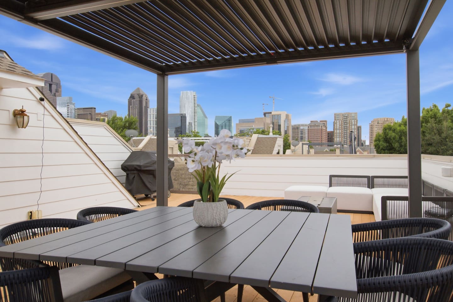 Rooftop patio with pergola, dining table, lounge seating, and unobstructed Dallas skyline views. One of the standout features of the property and a reason guests come back.
