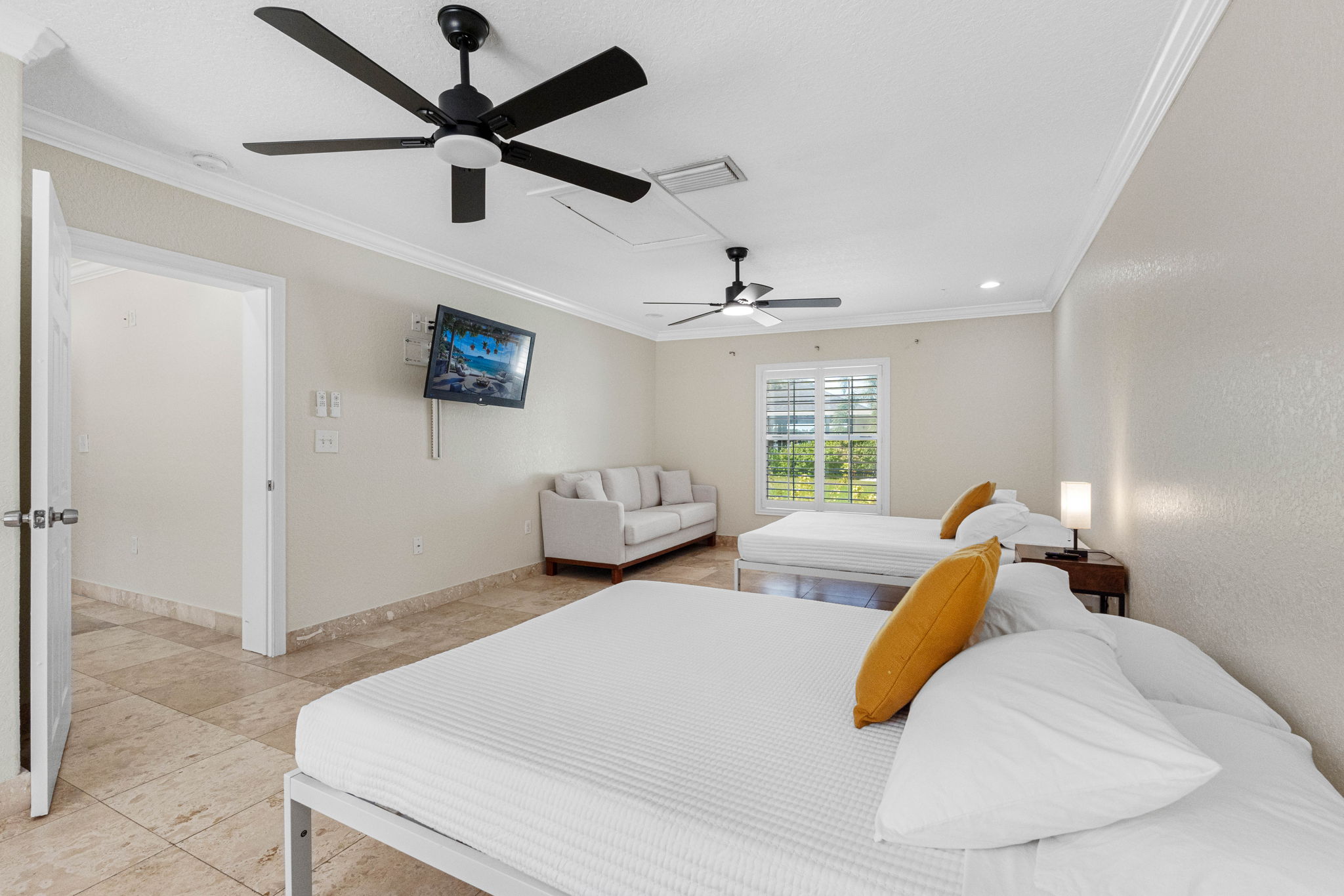 This bright and airy bedroom features two comfortable beds, a cozy sitting area, and a wall-mounted TV for ultimate relaxation.
