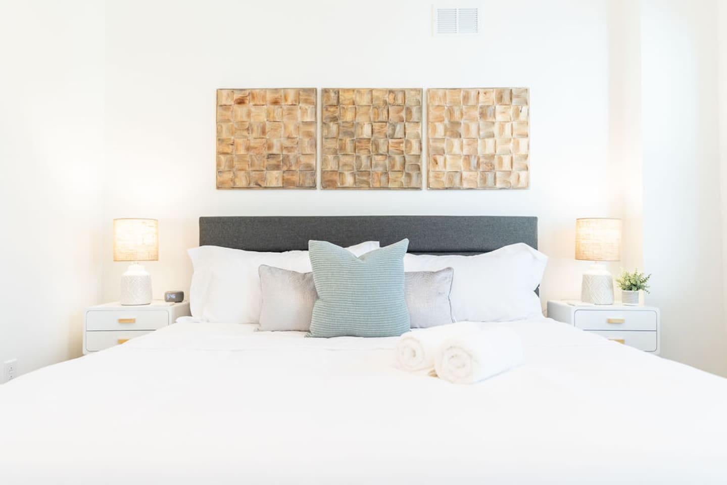 Zoomed-in view of the king-size bed with cozy pillows and lamps on each side, creating a warm and inviting atmosphere.