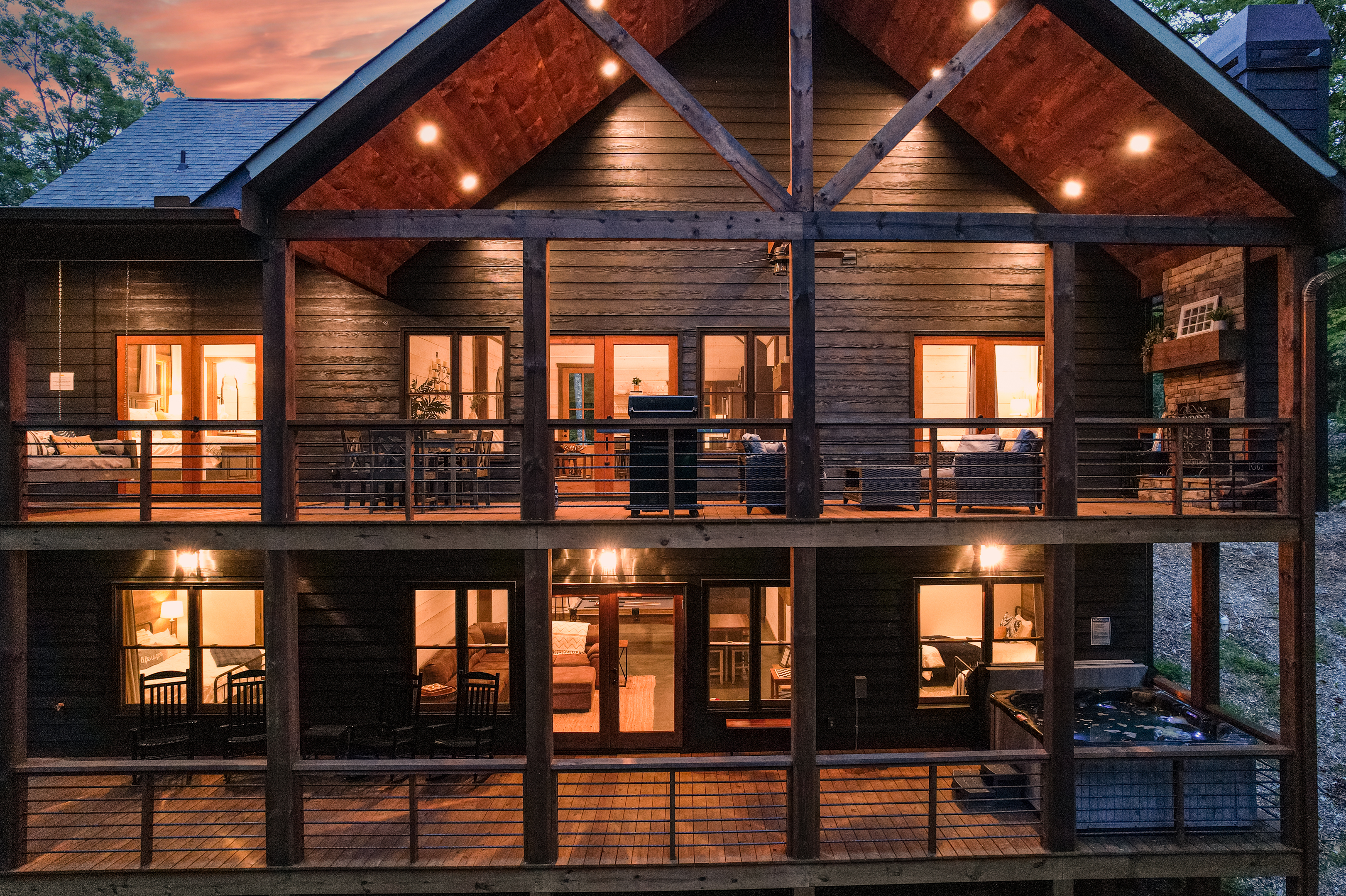 There are two levels of decks on the back of the house.  The back is surrounded by trees.  The top deck has a grill, dining area, large bed swing, and wood fireplace with seating area.  The lower deck has the 8 person hot tub and rocking chairs.