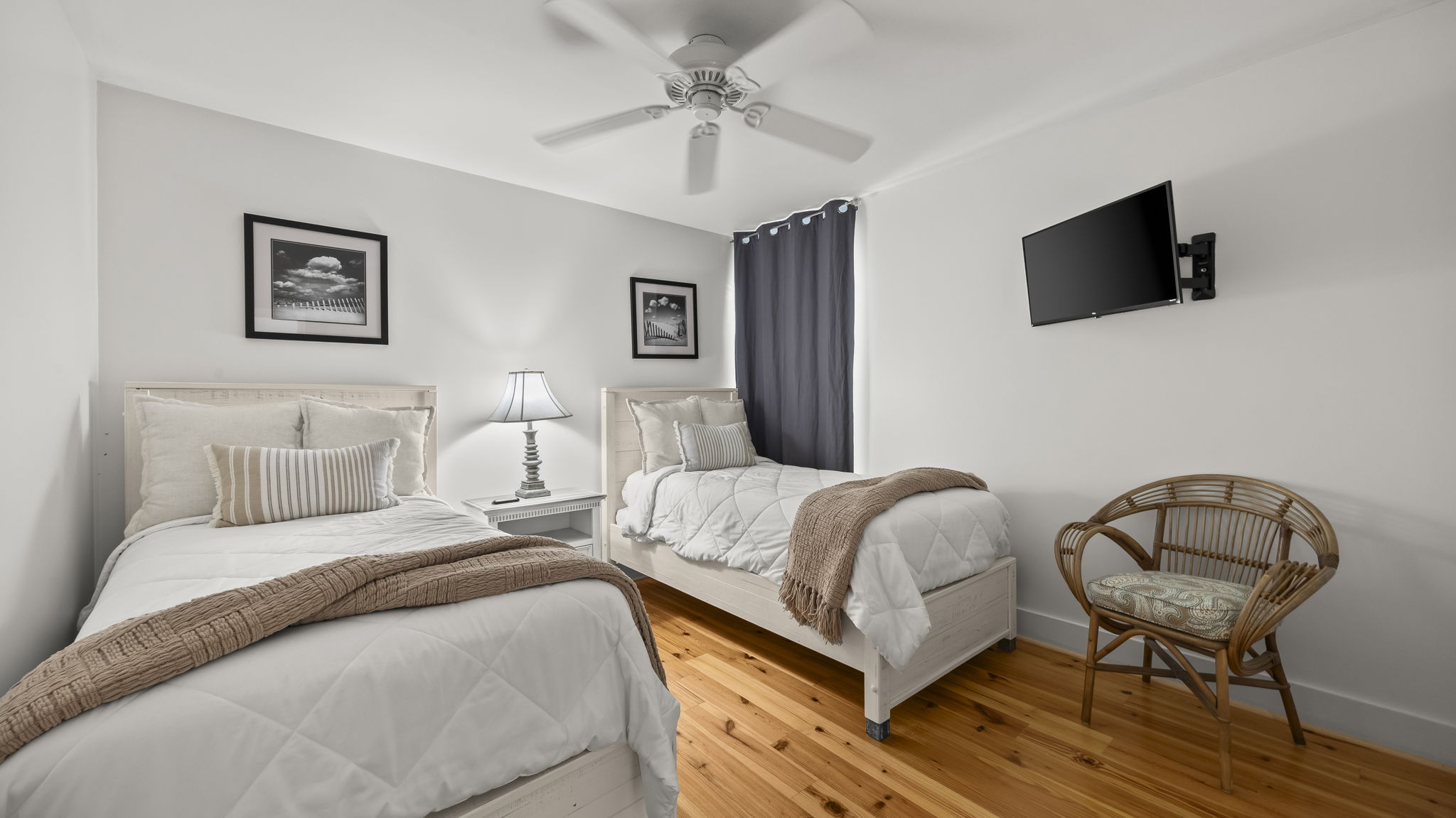 Welcome guests to the cozy guest bedroom in our Cotton Bayou condo, featuring twin beds with comfortable bedding and a charming coastal decor. Perfect for family or friends, this space ensures a restful stay in your home away from home.