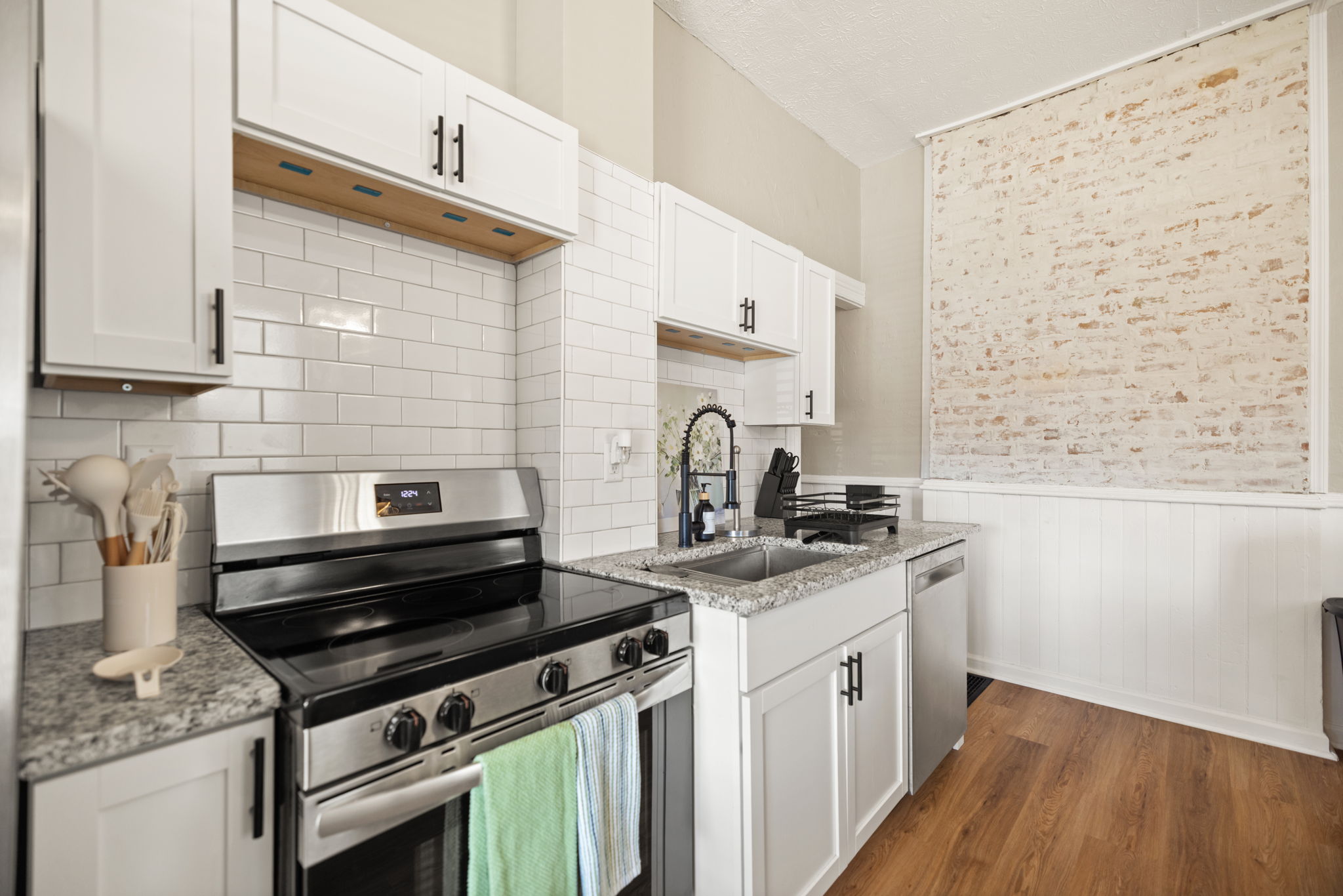 Fully equipped kitchen with range, white tile backsplash, and stainless appliances
