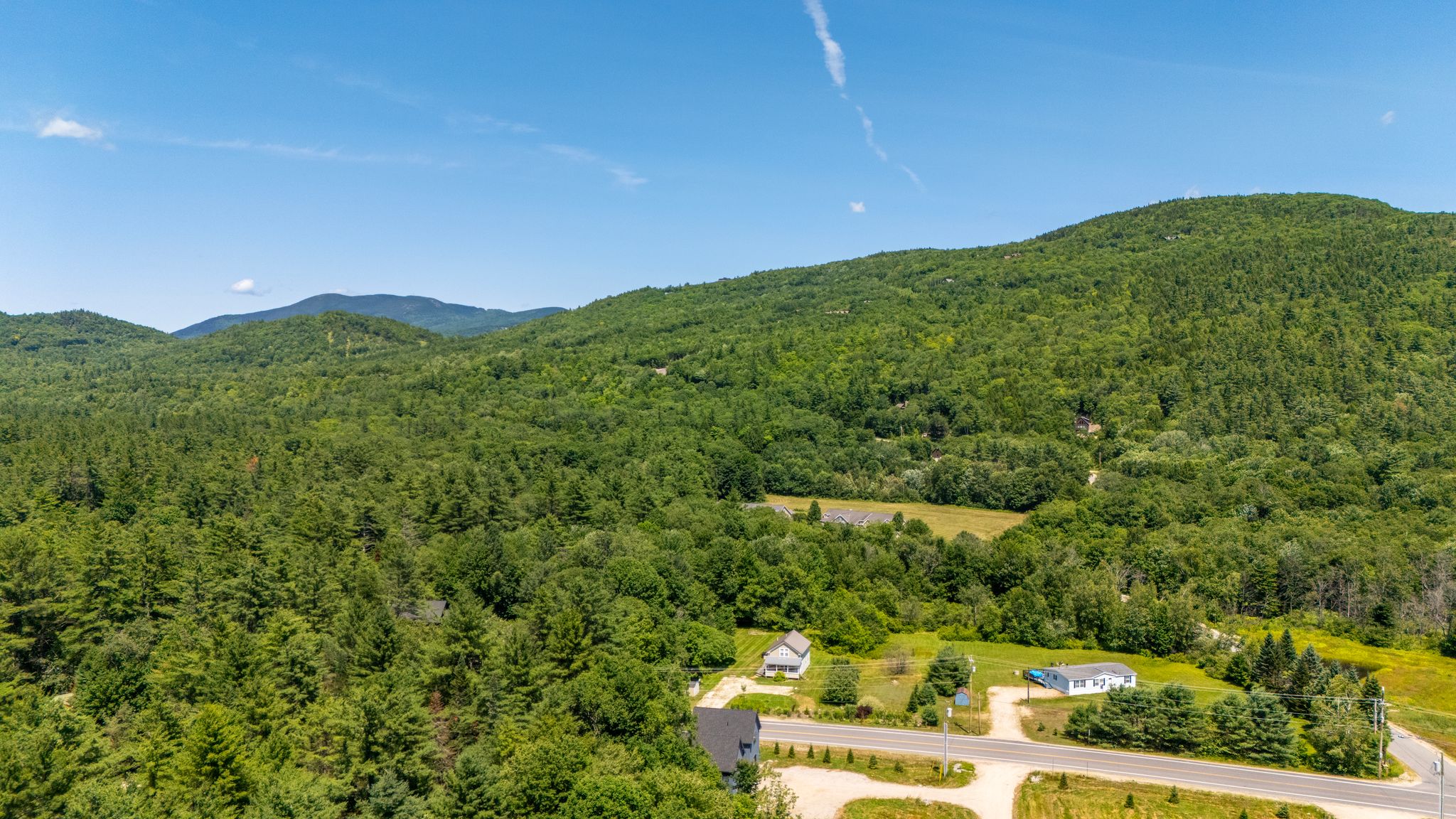 Escape to a scenic setting surrounded by rolling mountains, greenery, and open skies.