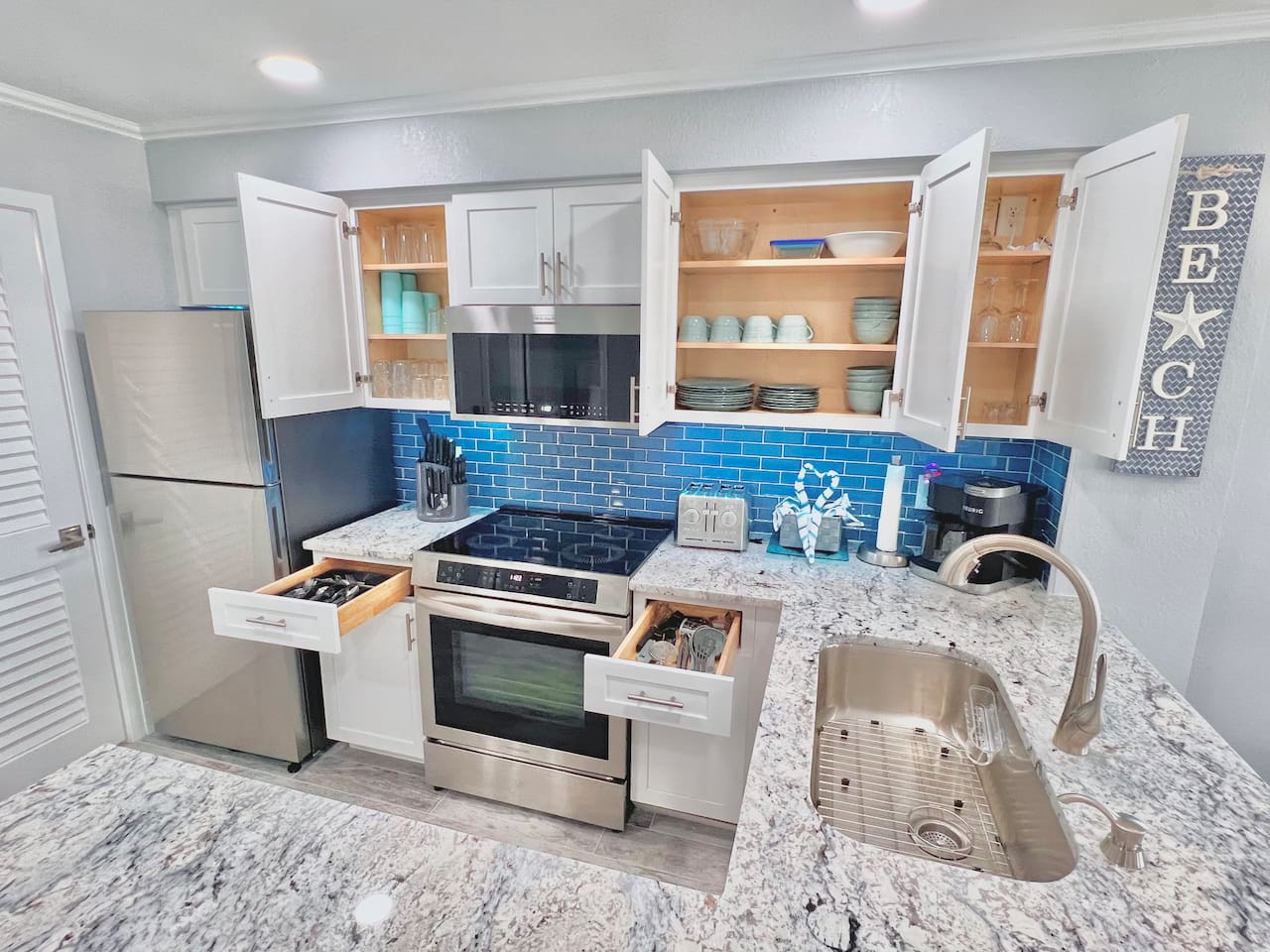 Very nice stainless steel appliances and cabinet space loaded with plates, bowls, cups, silverware, etc. 