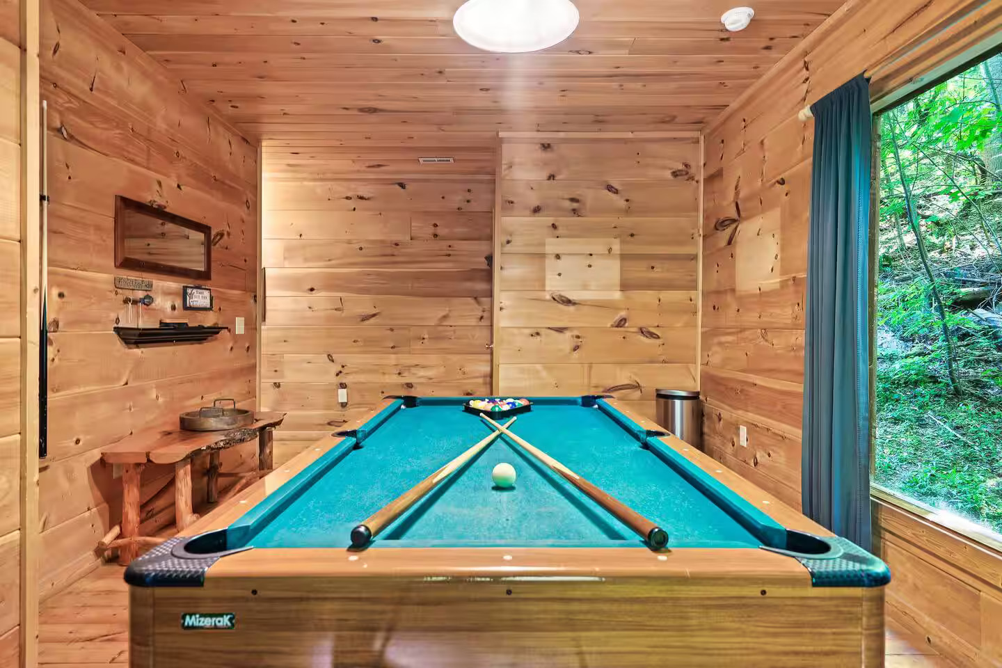 The game room includes a sleek pool table, ideal for friendly competition. Natural wood tones and scenic views create a warm and relaxed atmosphere for unwinding.