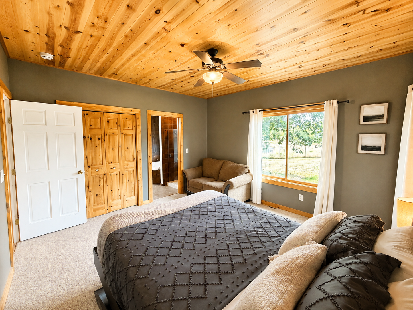 Another view of this roomy bedroom highlights the generous floor space, natural light and comfortable sitting area and bathroom just steps away.
