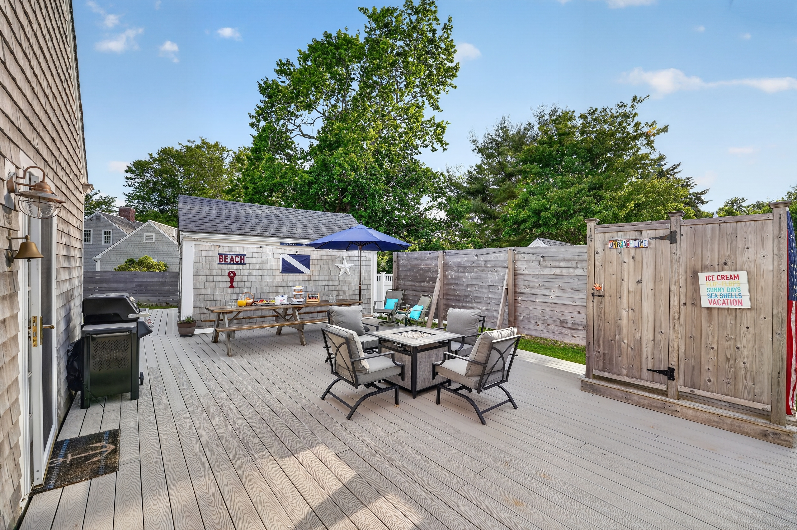Spacious outdoor deck featuring dining, lounge seating, a fire table, and grill—perfect for entertaining.