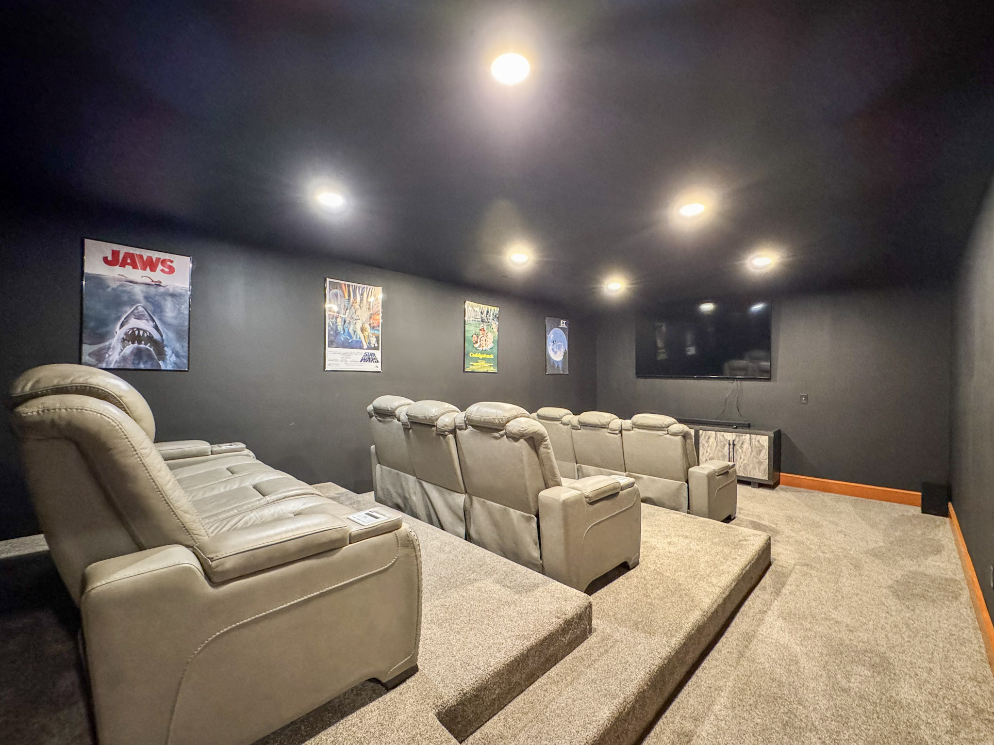 Theater room with a smart TV and six power recline seats.