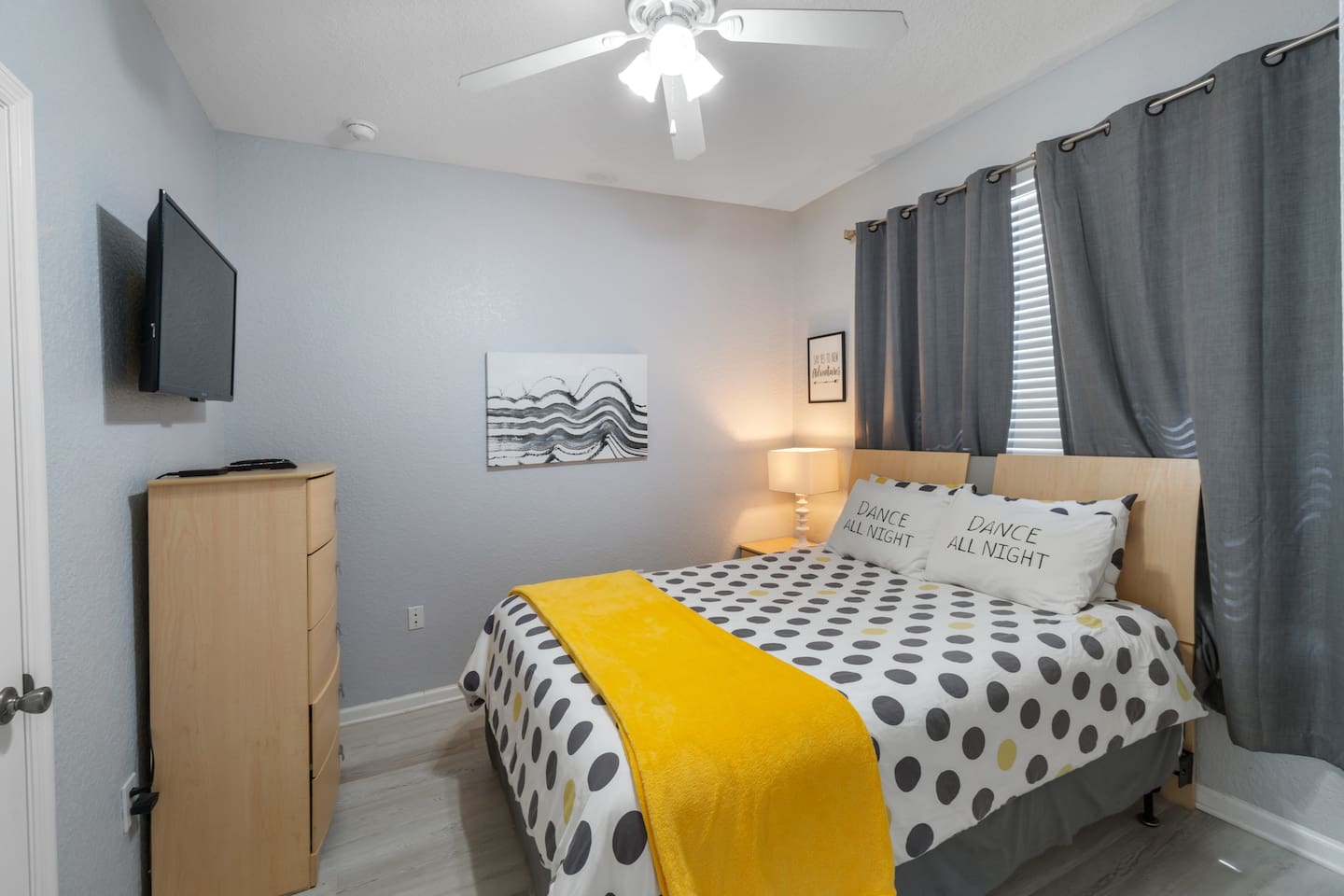 - Cozy bedroom with queen bed, modern polka dot bedding, and yellow throw  
- Soft lighting and ceiling fan create a comfortable and restful environment  
- Perfect for couples or solo travelers seeking a relaxing night’s sleep  