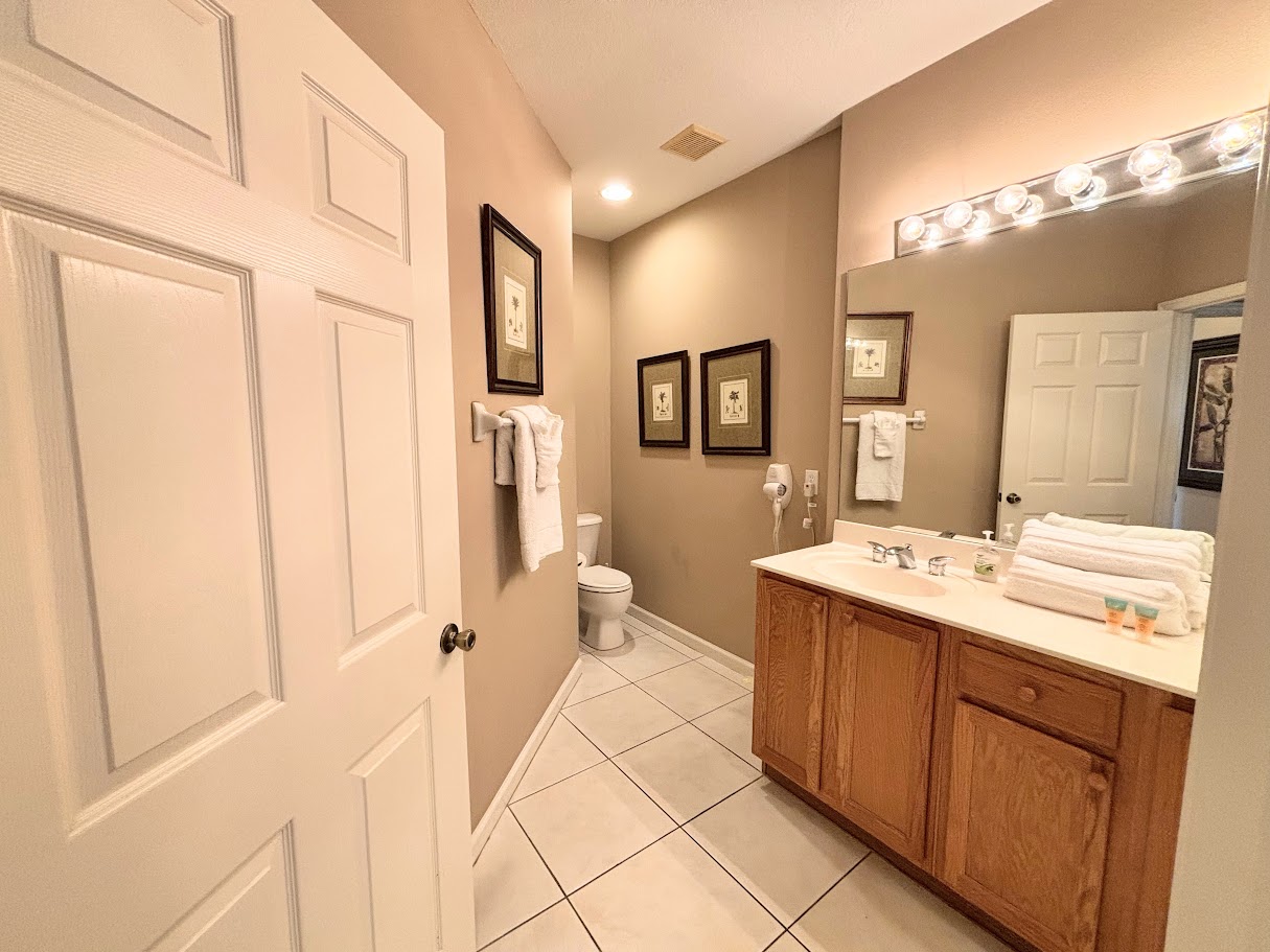 Clean and spacious bathroom featuring a large vanity, bright mirror lighting, tile flooring, and plenty of counter space.