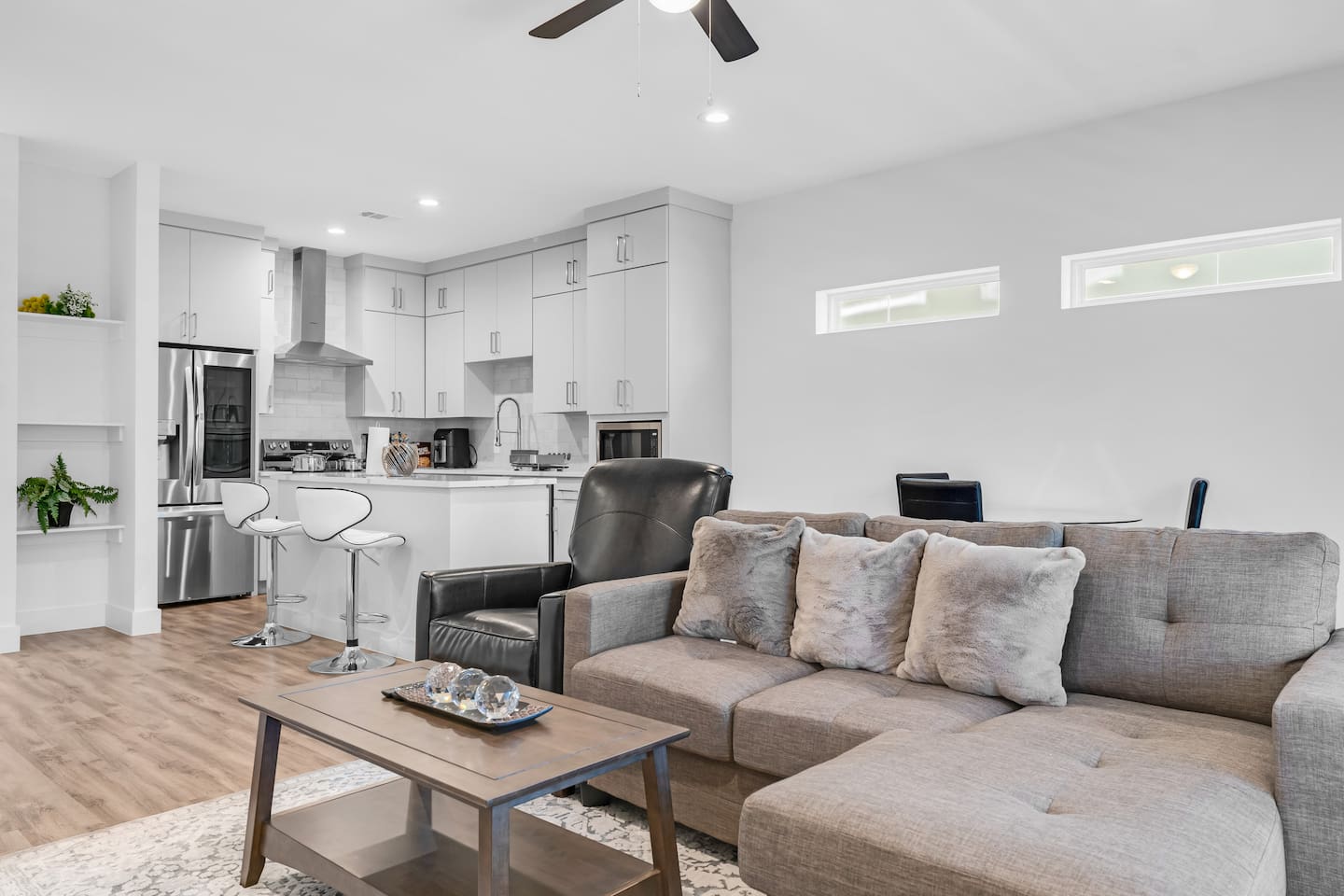 Spacious open-concept living area with a sleek sectional, elegant decor, and direct flow into the modern kitchen.