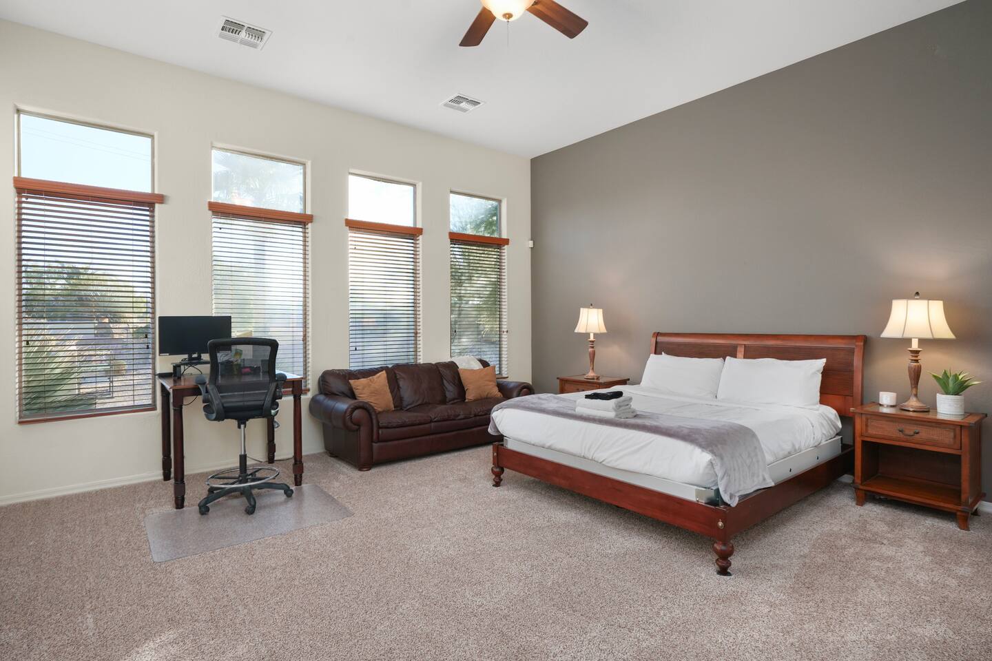 Bright primary bedroom featuring a dedicated workspace and comfortable seating