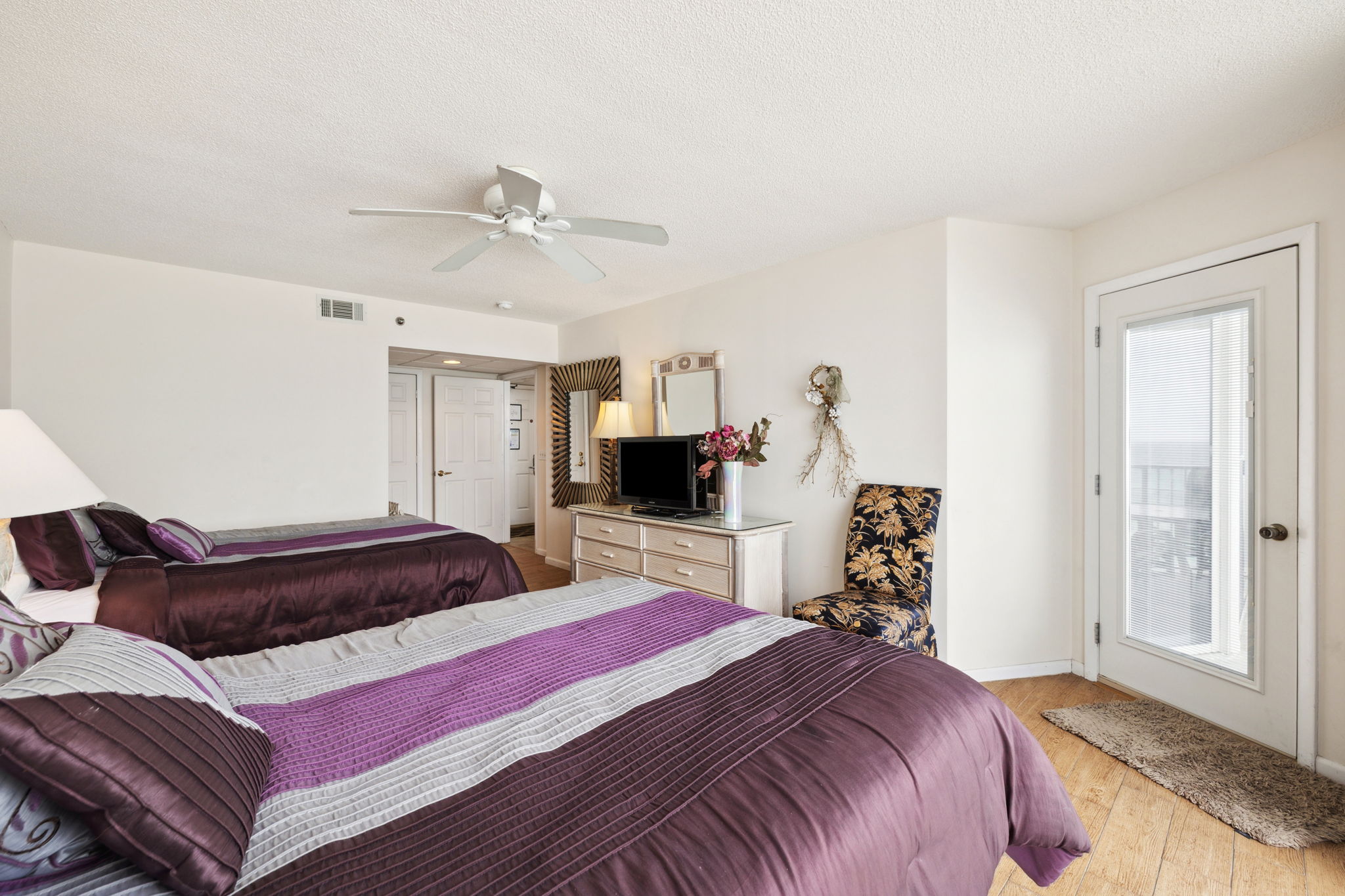 Double queen bedroom with floor to ceiling windows showcasing the beautiful Emerald Gulf waters and balcony access from bedroom
