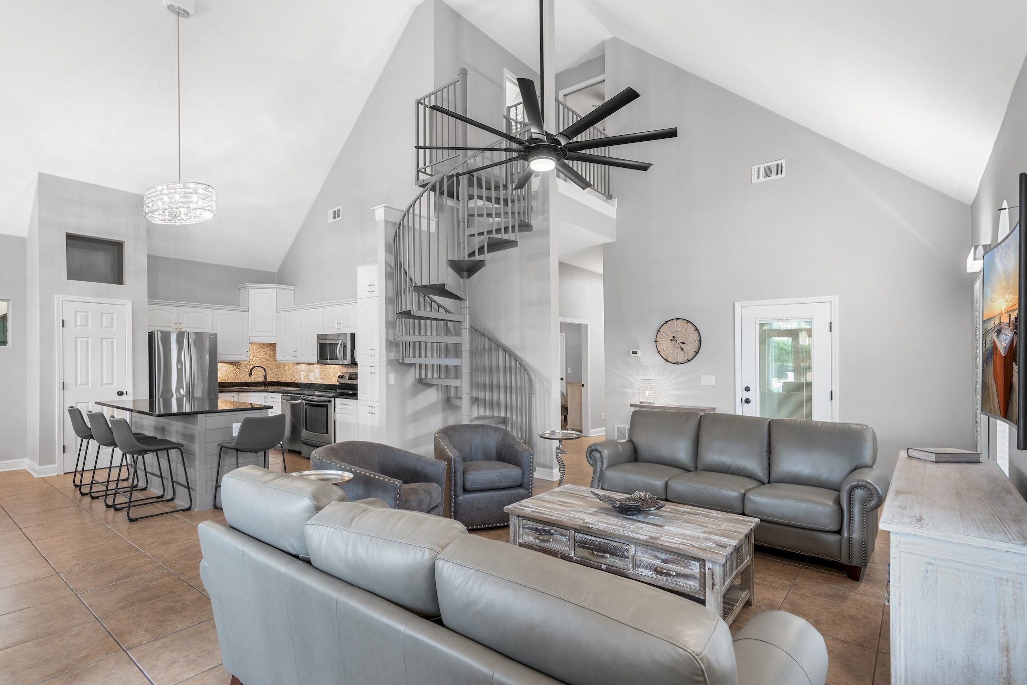 Open‑concept living area with vaulted ceilings and modern coastal décor