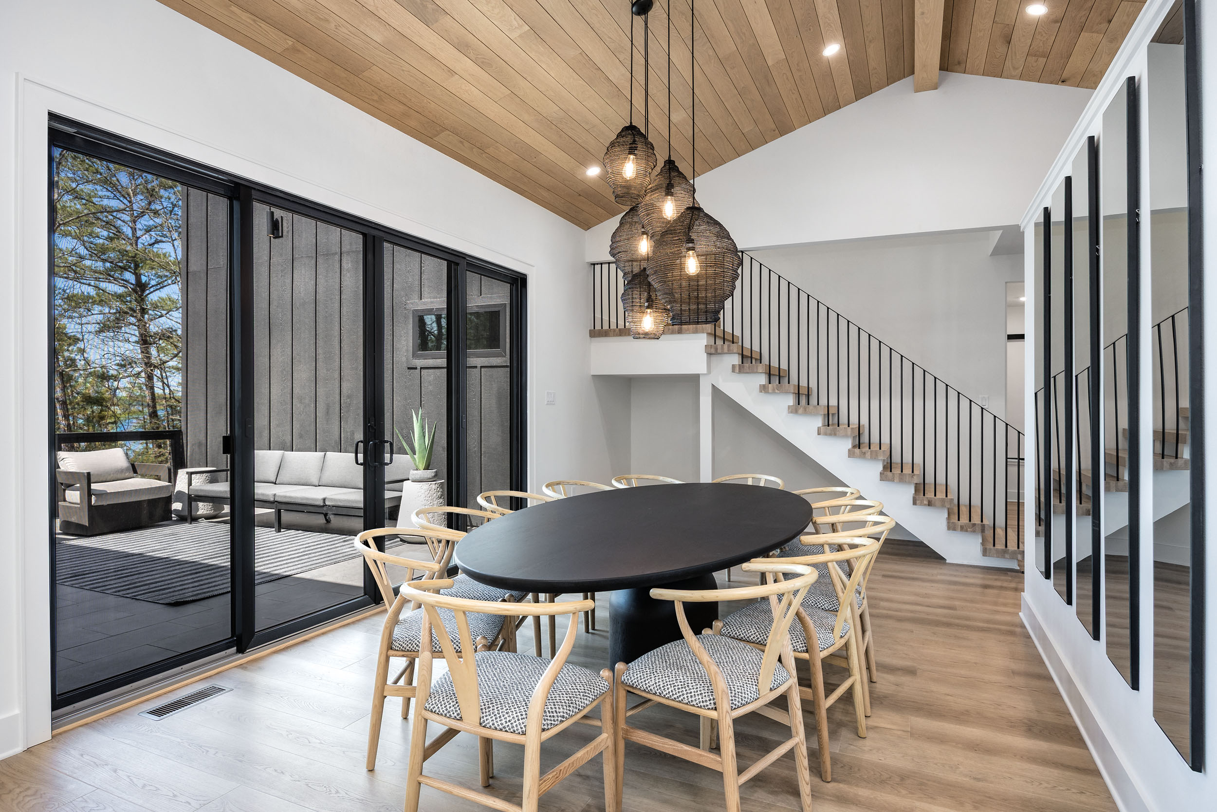 Gather your group around the large dining table with views of the outdoor deck and woods beyond—perfect for shared meals and memories.