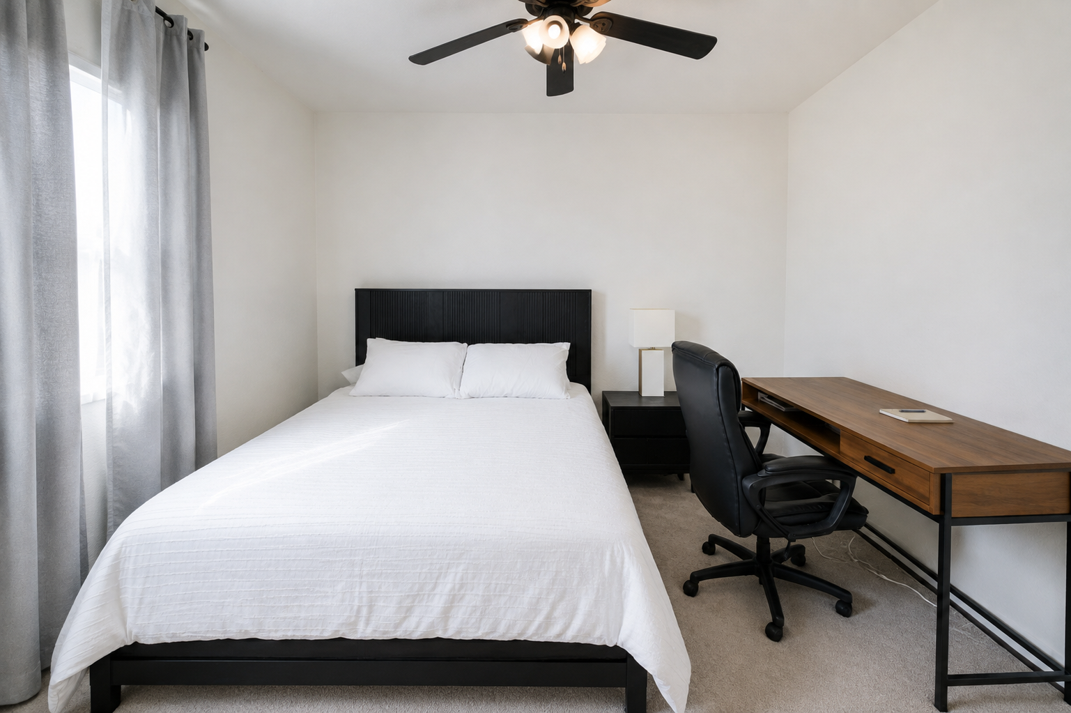 Bedroom with queen bed, dedicated workspace, ceiling fan, and a simple setup for rest or remote work.