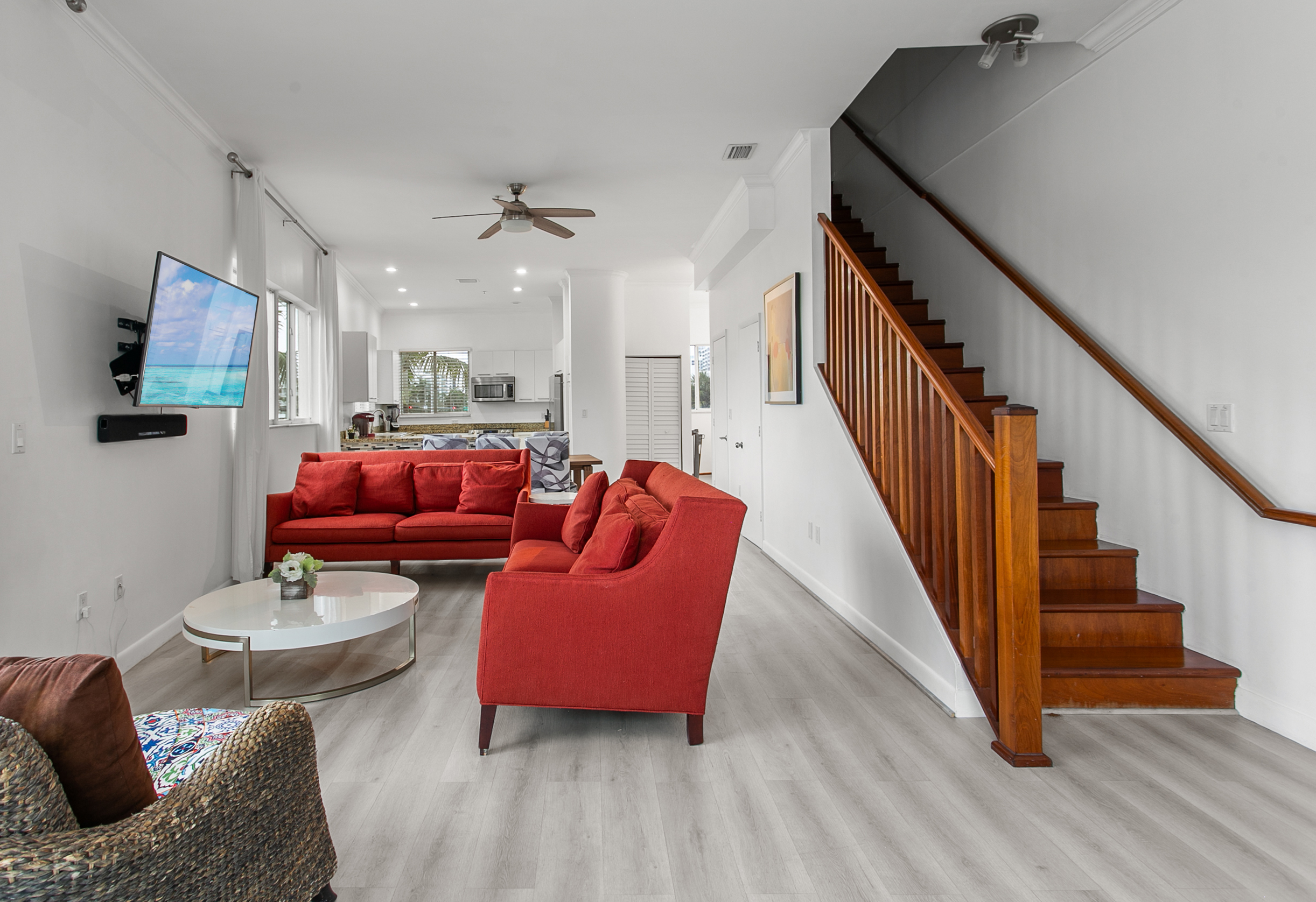 Huge sunny corner living room with two sofas, a daybed, and a swing chair. Private balcony with city and waterway views.