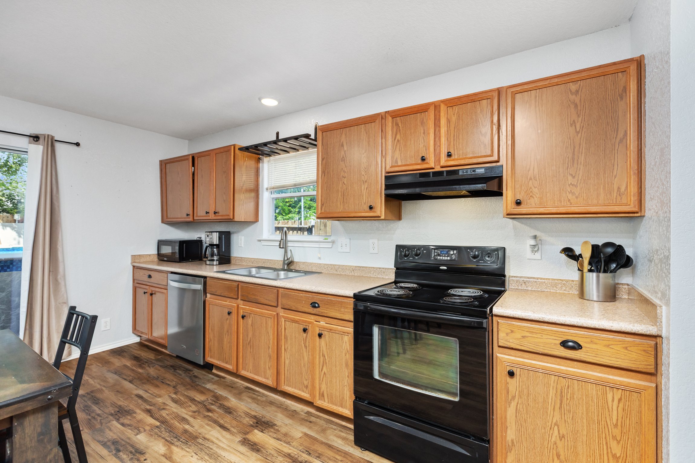 Fully equipped kitchen with range, oven, stainless dishwasher, double sink, and wood cabinetry. Hardwood floors and ample counter space for home-cooked meals. Everything your group needs for a full stay.