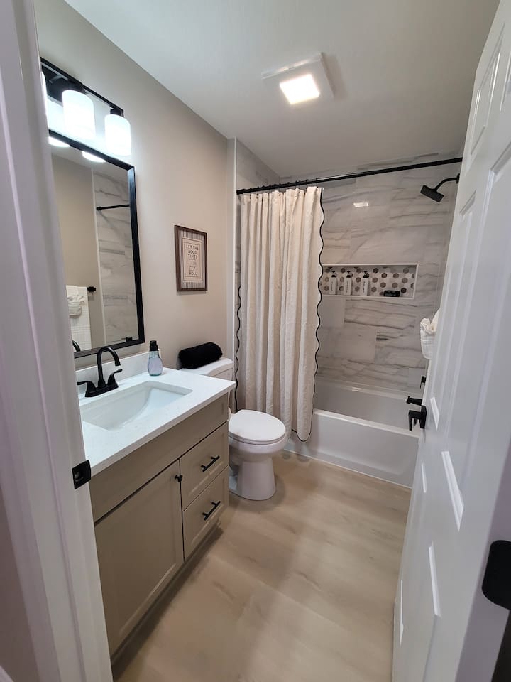 Freshly renovated and beautifully appointed, this guest bathroom features modern finishes, a tiled tub/shower combo, and all the essentials for a comfortable stay.