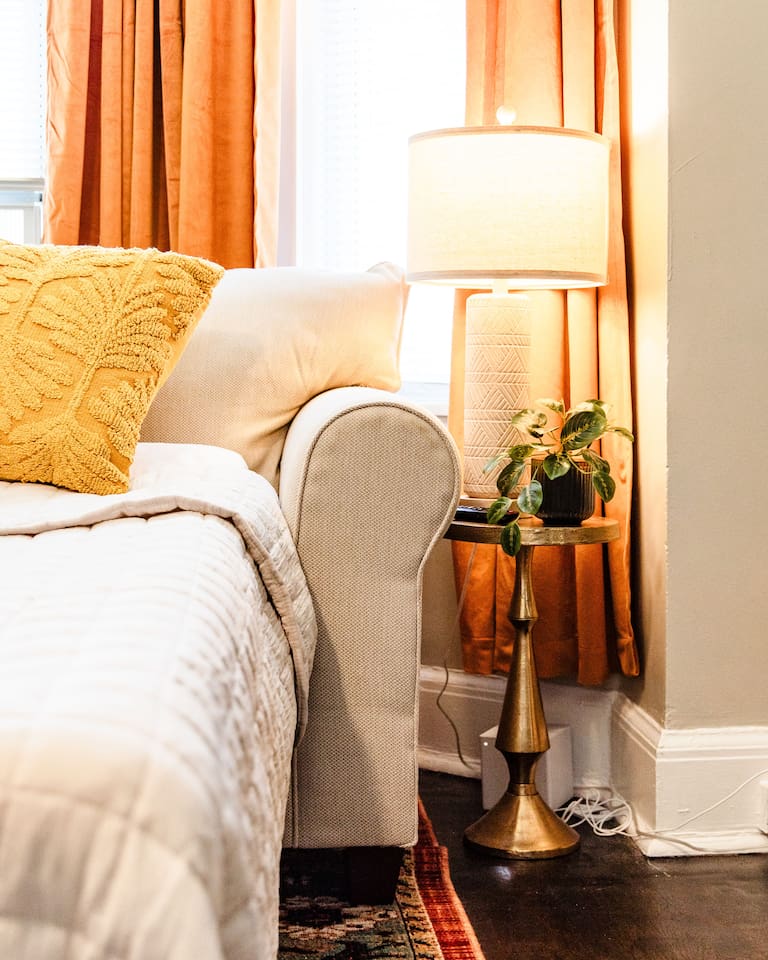 Cozy sofa bed with a side table and lamp, creating a comfortable and functional space for lounging, reading, or hosting overnight guests.