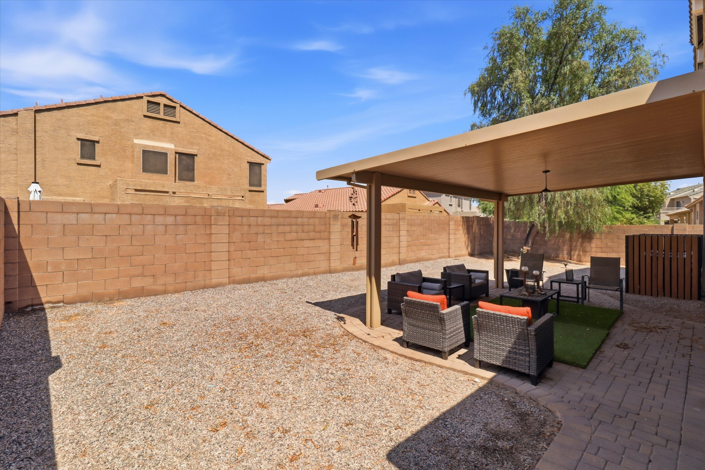 Covered backyard patio with outdoor seating and an open gravel yard for extra space outside.