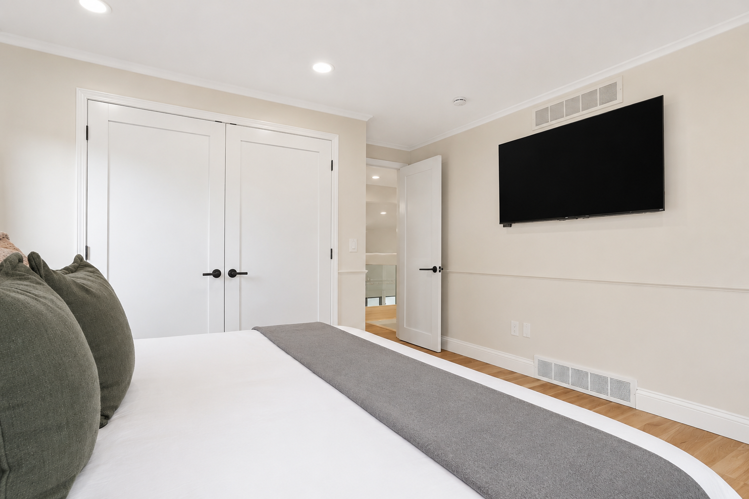 Bright, modern bedroom with a wall-mounted TV, clean neutral finishes, and a comfortable minimalist design. A simple, relaxing space ideal for unwinding and rest during your stay.