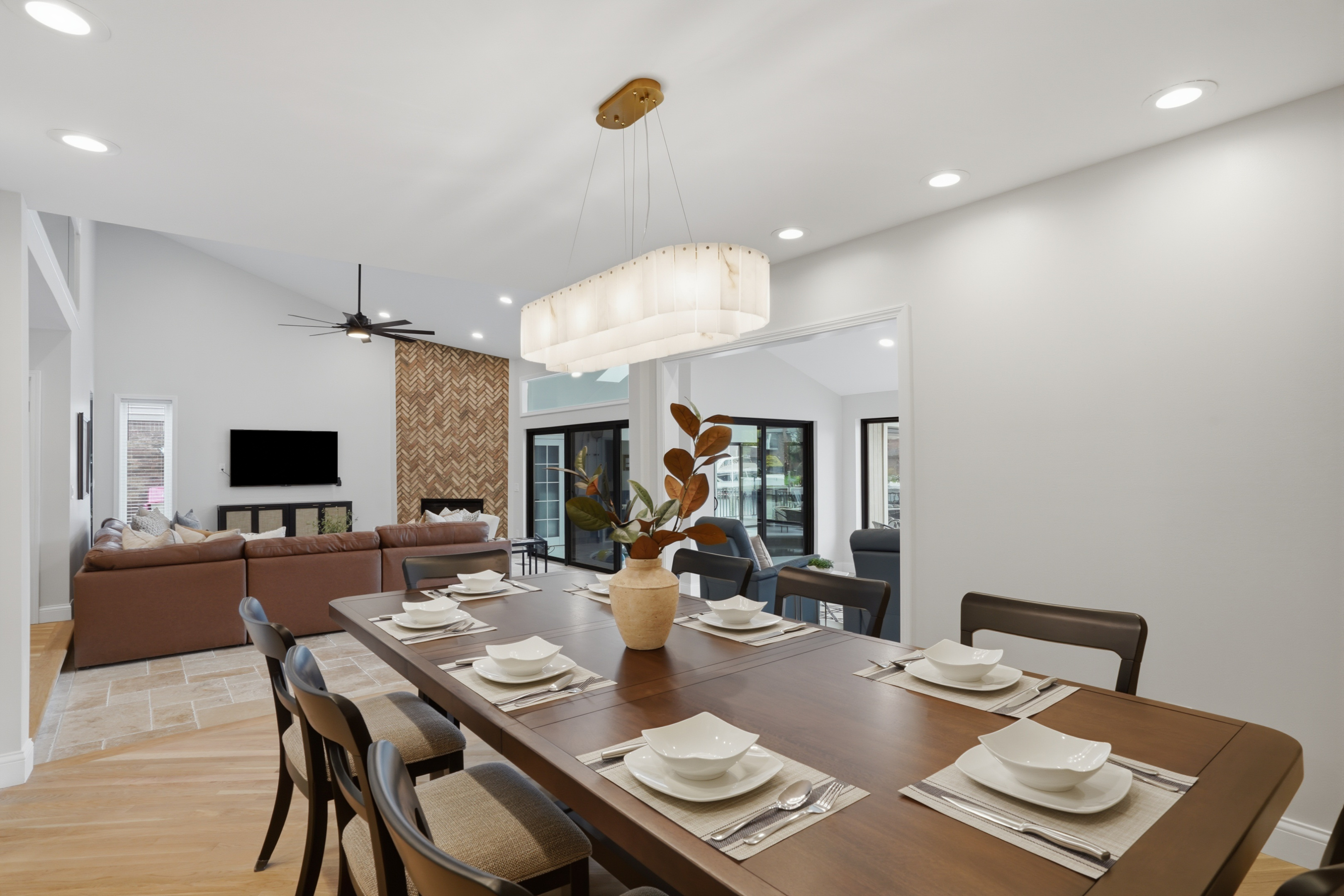Elegant dining room with a large table, modern seating, and a bright chandelier centerpiece. Clean, minimalist design perfect for family meals, gatherings, and entertaining in a stylish, upscale setting.