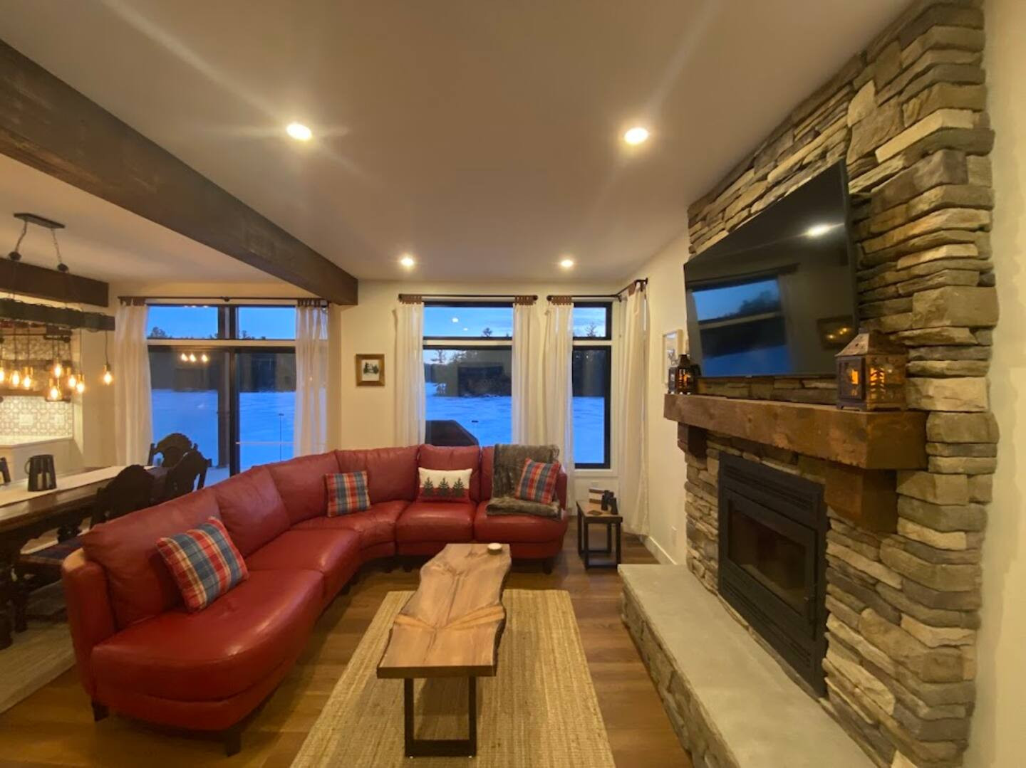 Living room seating in front of wood-burning fireplace and 65 inch smart TV