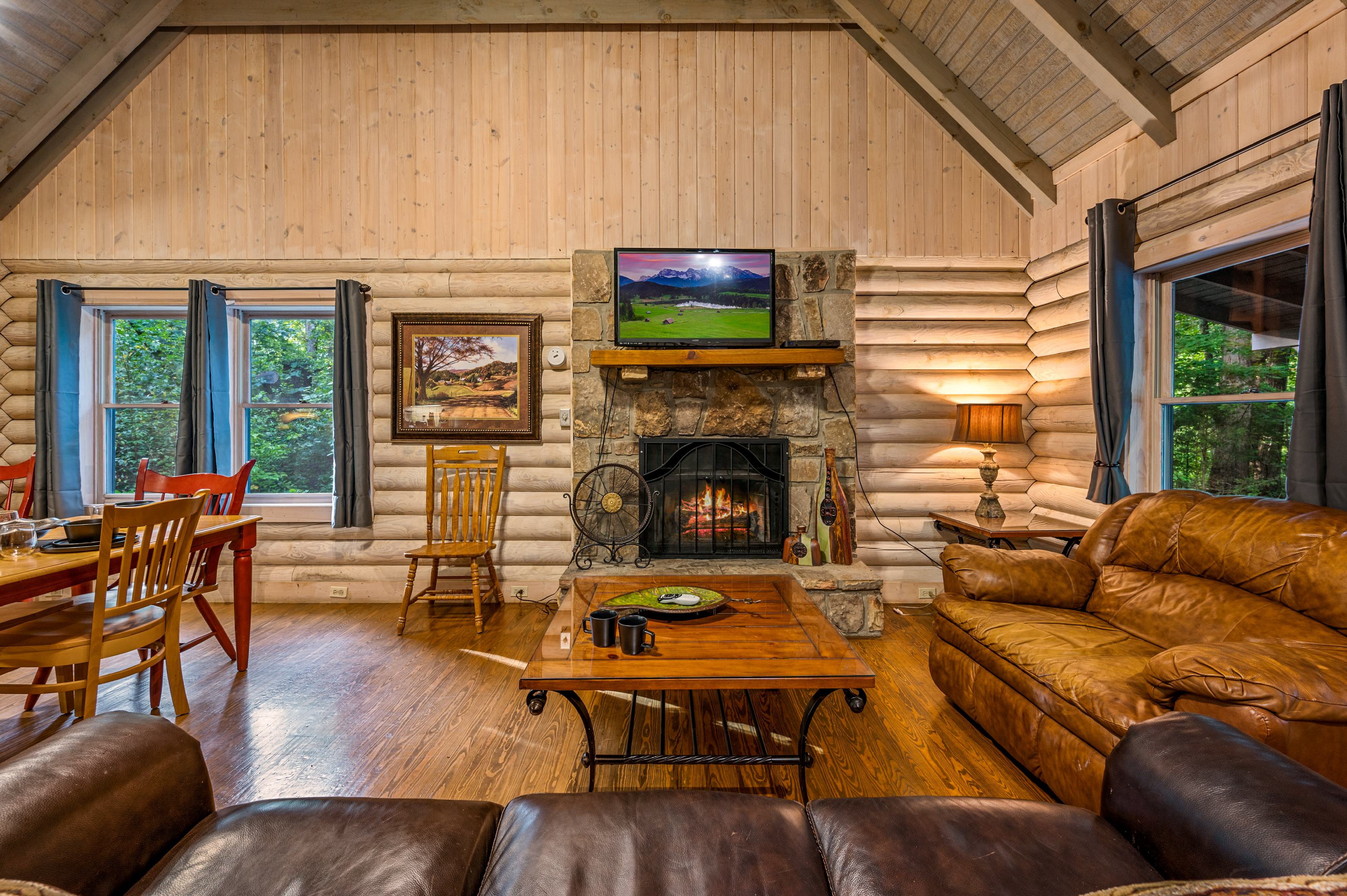 Cozy up by the fireplace in this rustic cabin living room with TV & plush seating.