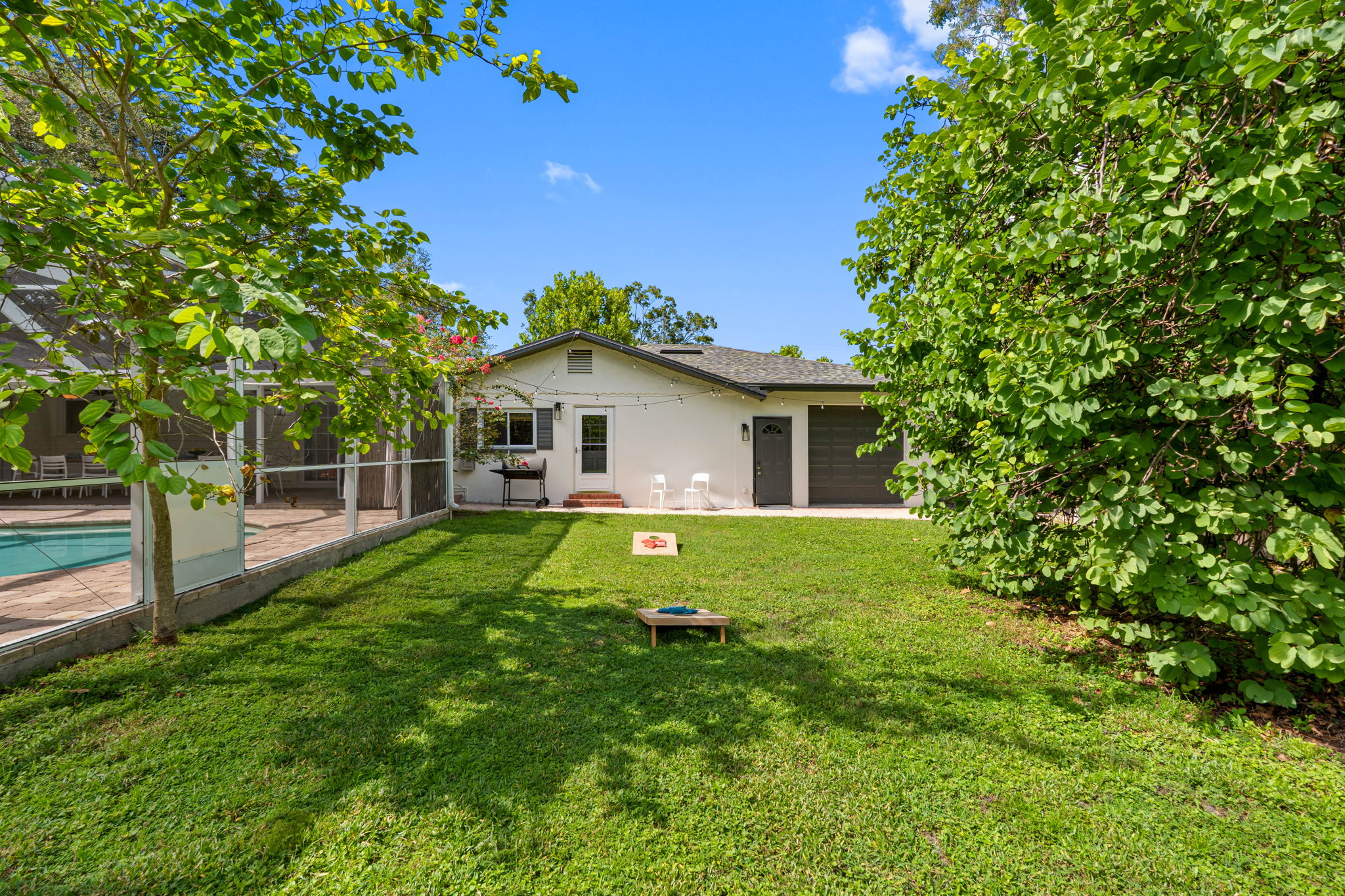 This expansive lawn area surrounds the screened pool, offering plenty of room for play, entertaining, or relaxing under the Florida sunshine.
