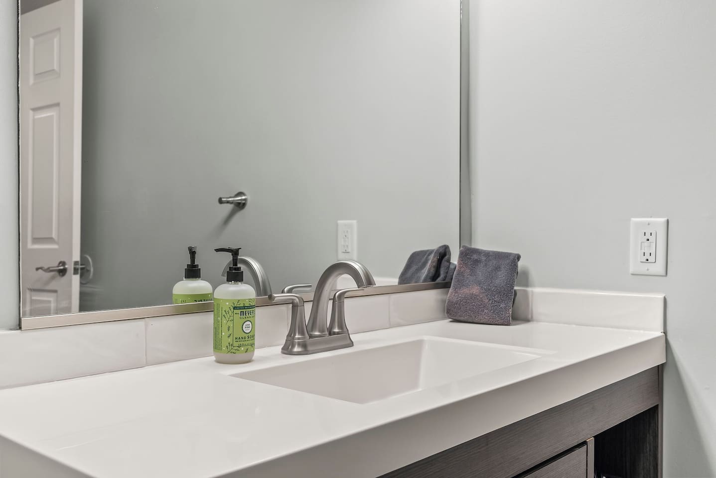 Close-up of the sink and vanity featuring a modern faucet, clean countertop, and provided hand soap.