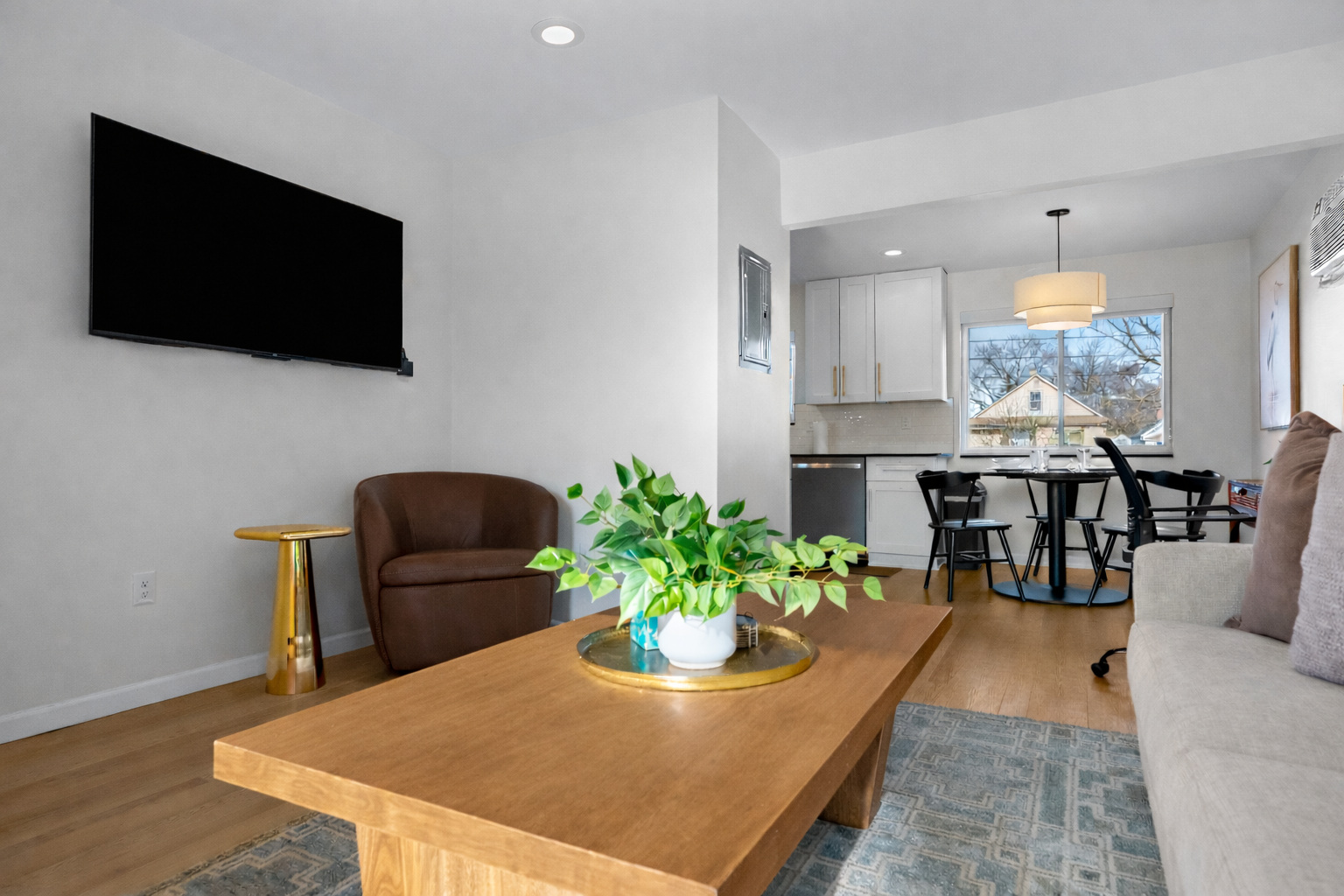 Open, airy living area with smart TV, cozy seating, and seamless flow into the kitchen and dining space—perfect for relaxing or sharing meals.
