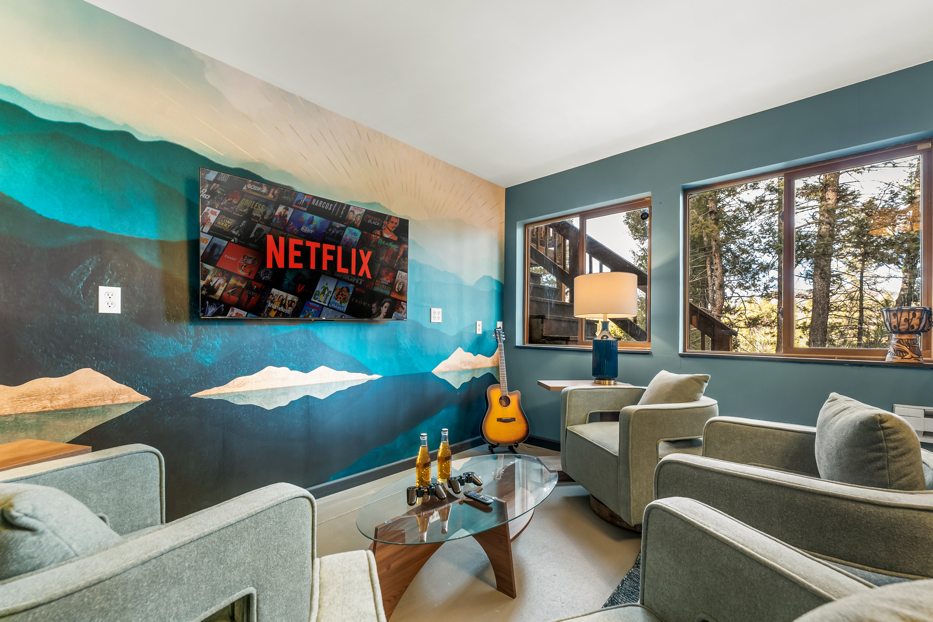 🎬🎮 Movie/Game Room lounge: big-screen TV 📺, comfy chairs, and a bold mountain mural—perfect for pre-game hangouts, movie marathons, and a little guitar time 🎸✨