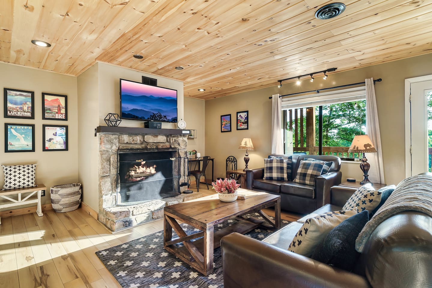 The main living room area, with a real wood-burning fireplace (1 of 3!) and an open floor plan connecting it to the kitchen and dining area. Walk out to the covered porch with hot tub.
