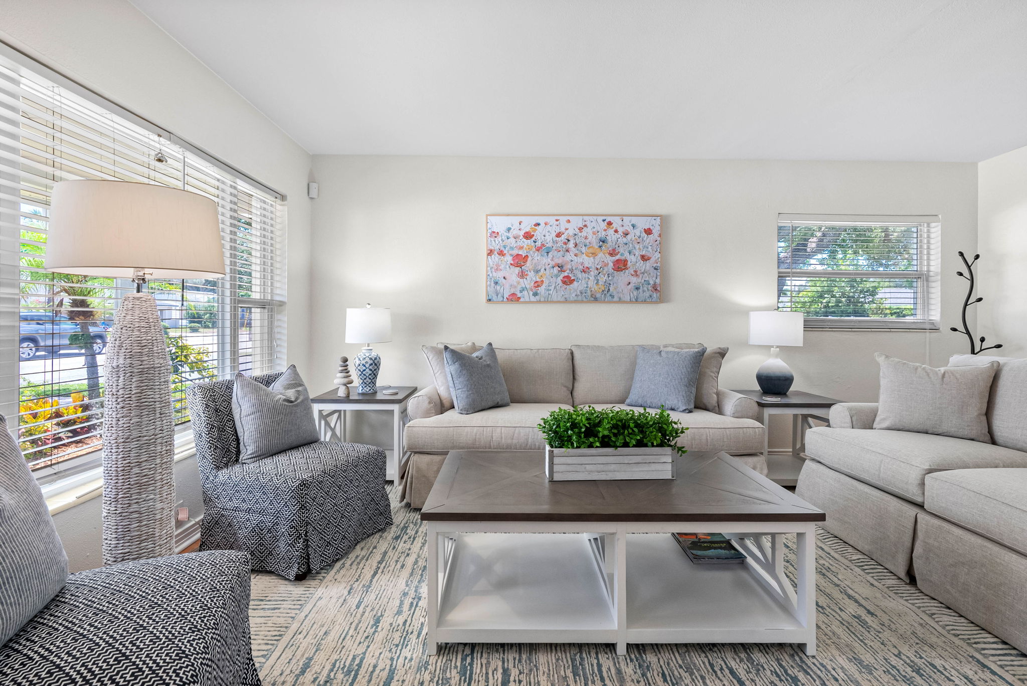 The room features two oversized, cloud-like sofas, a textured armchair with oversized cushions, and two woven poufs—offering plenty of space for families and groups to gather.