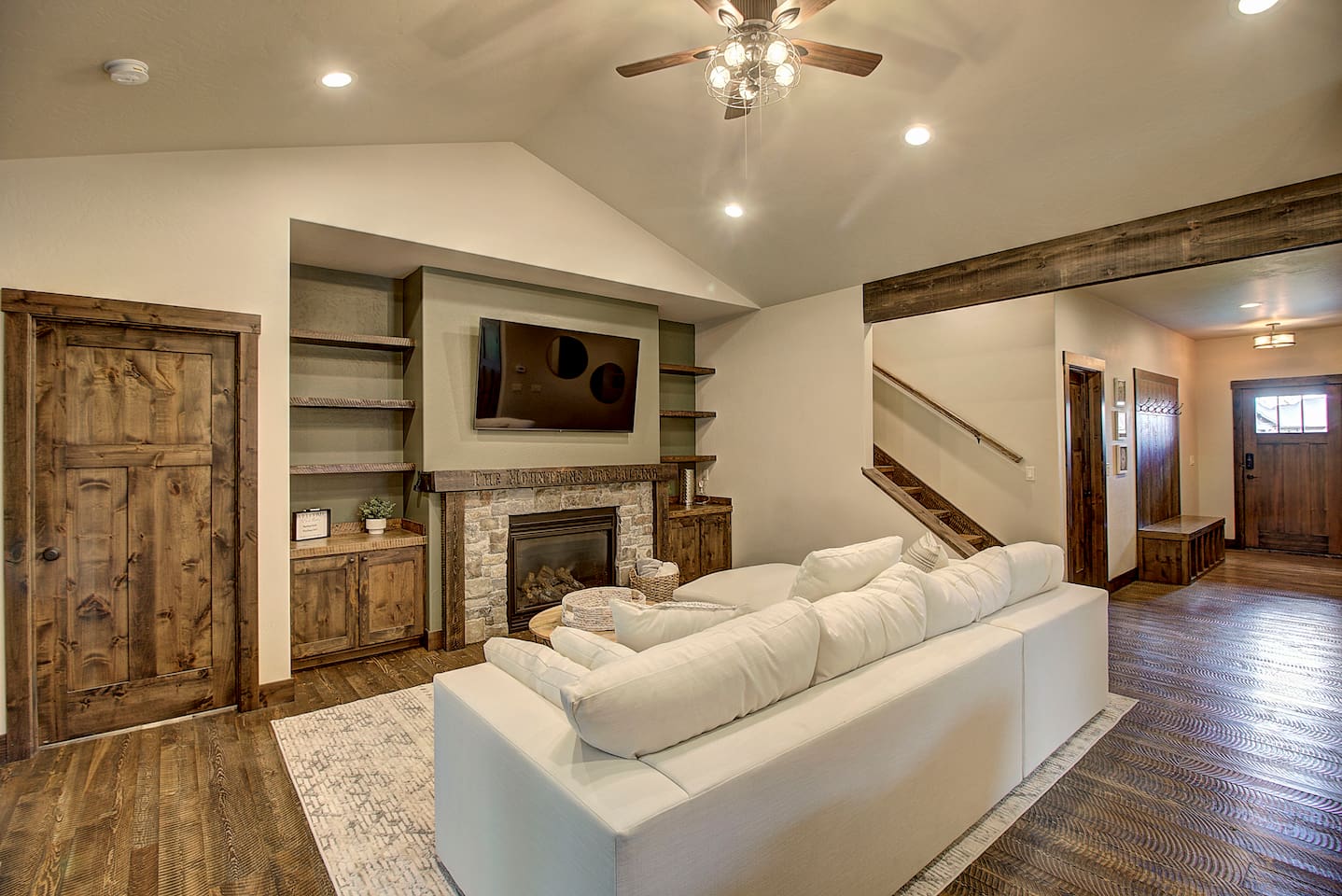 Curl up on the oversized sectional by the fire, warm and inviting living room featuring a stone fireplace, built-ins.